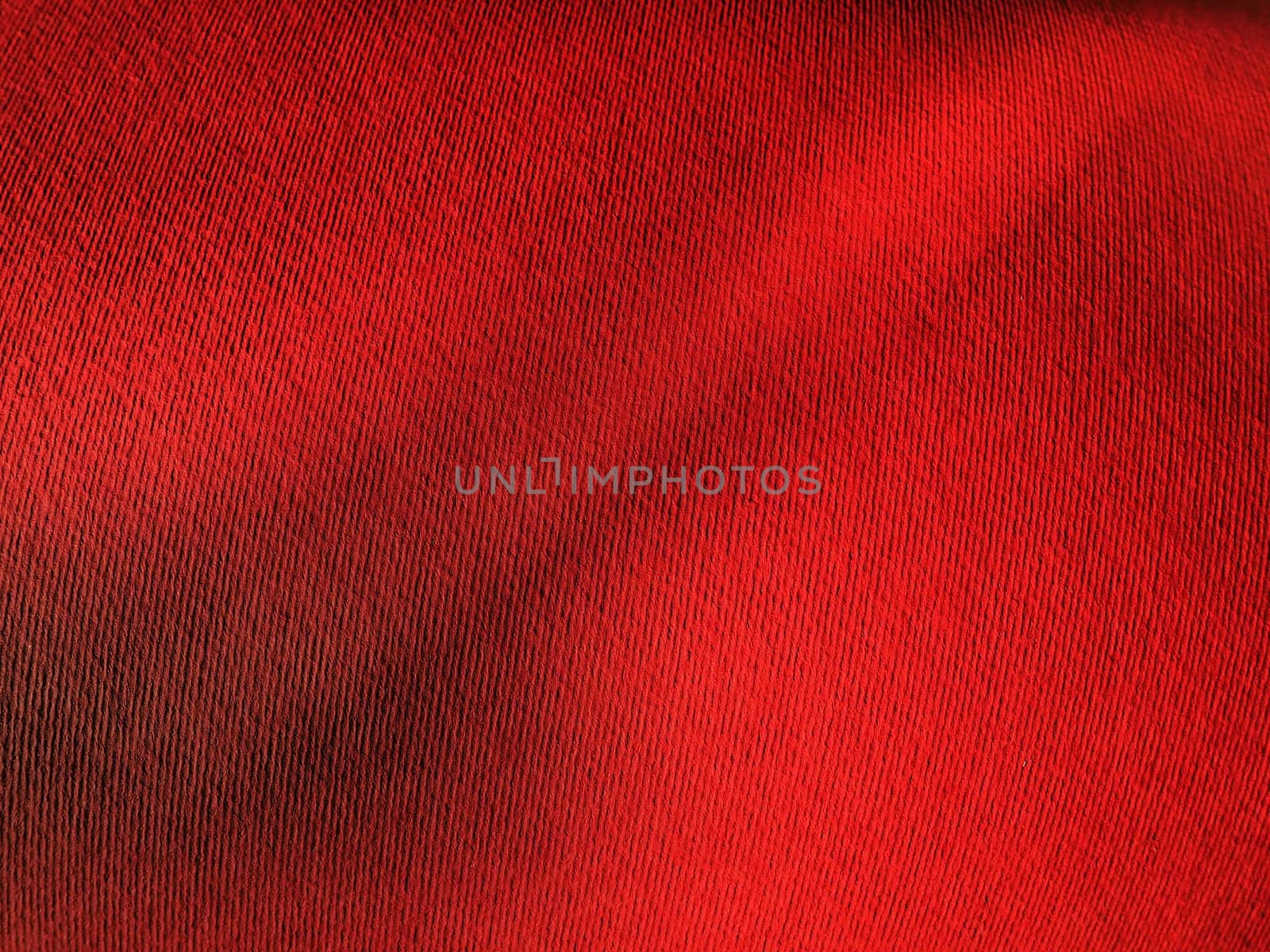 Abstract red background with texture. Close-up of paper surface with light and color gradient. Side lighting. Bright crimson backdrop.