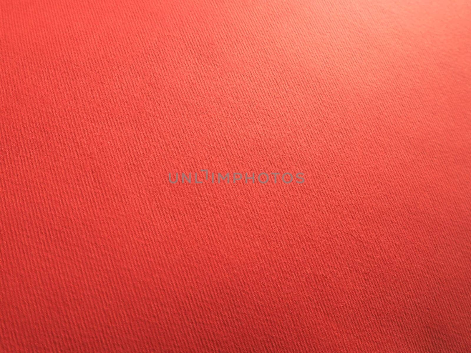 Abstract red background with texture. Close-up of paper surface with light and color gradient. Side lighting. Bright crimson backdrop.