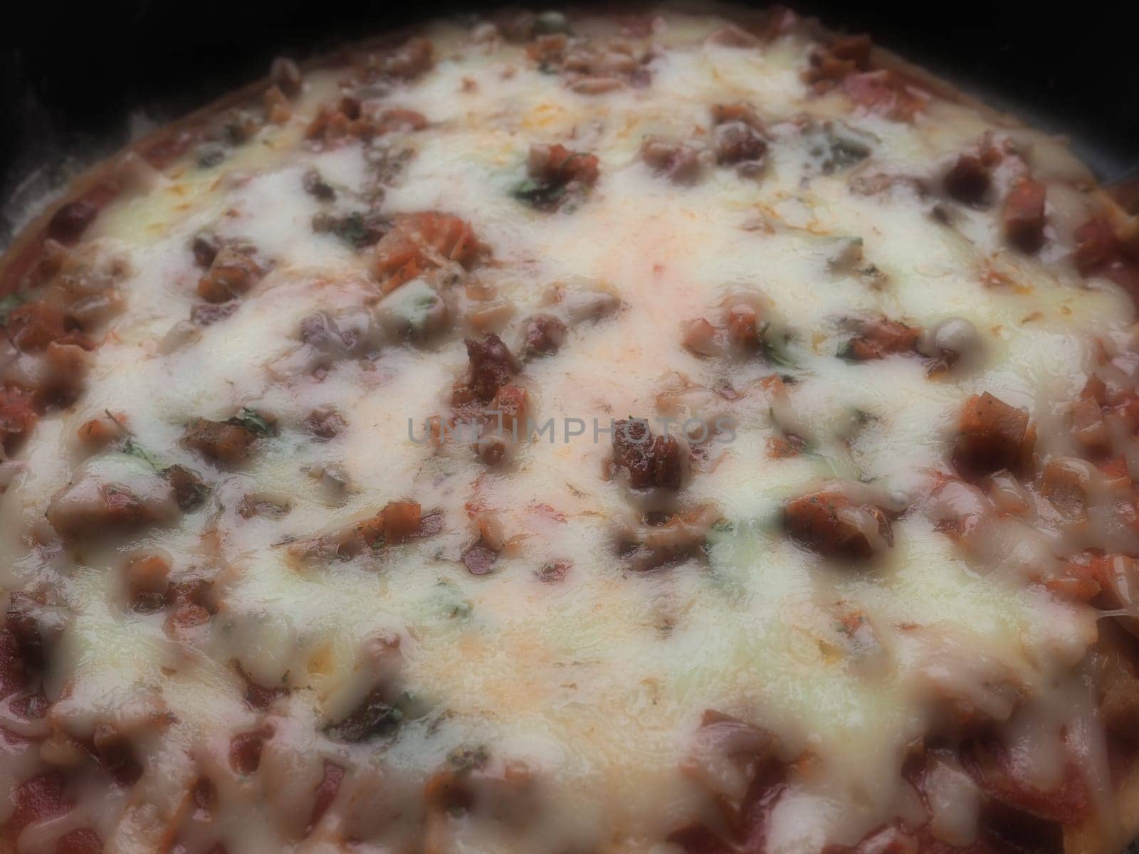 whole pizza close up. Delicious, juicy round pizza with tomatoes, salami. The melted cheese pours over the surface of the baked cake. Counter light. Soft blurred focus.