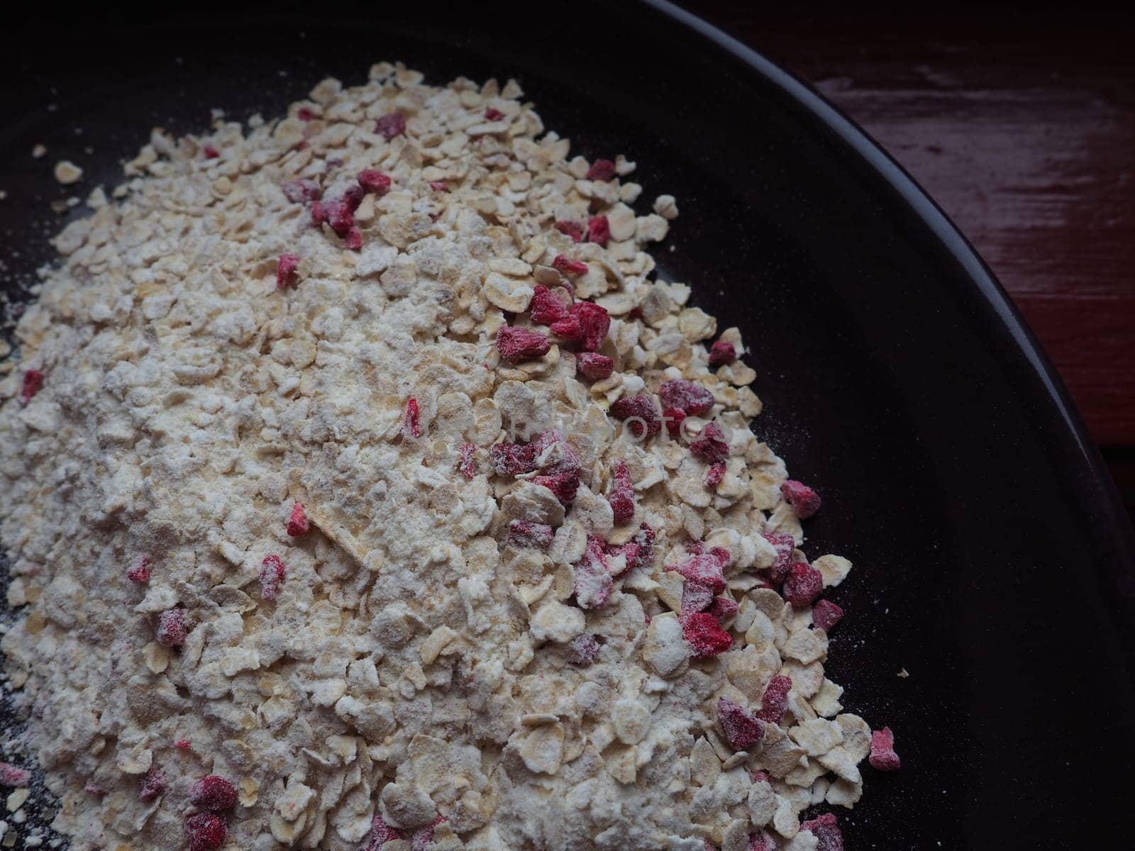 Organic Granola Cereal with oats, powdered sugar and dry raspberries. Healthy muesli as a dry mix. An antidiabetic, low calorie, healthy diet. Black utensils.