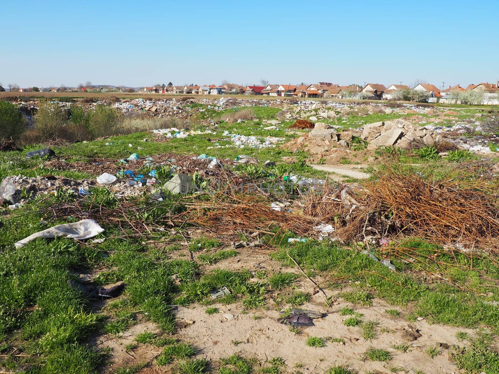 Sremska Mitrovica, Chalma, Serbia, 5 April 2021.garbage dump near the village. Chaotic unofficial dump. Plastic, bags, paper, glass, biological waste. Green grass next to dirt. Ecological catastrophy