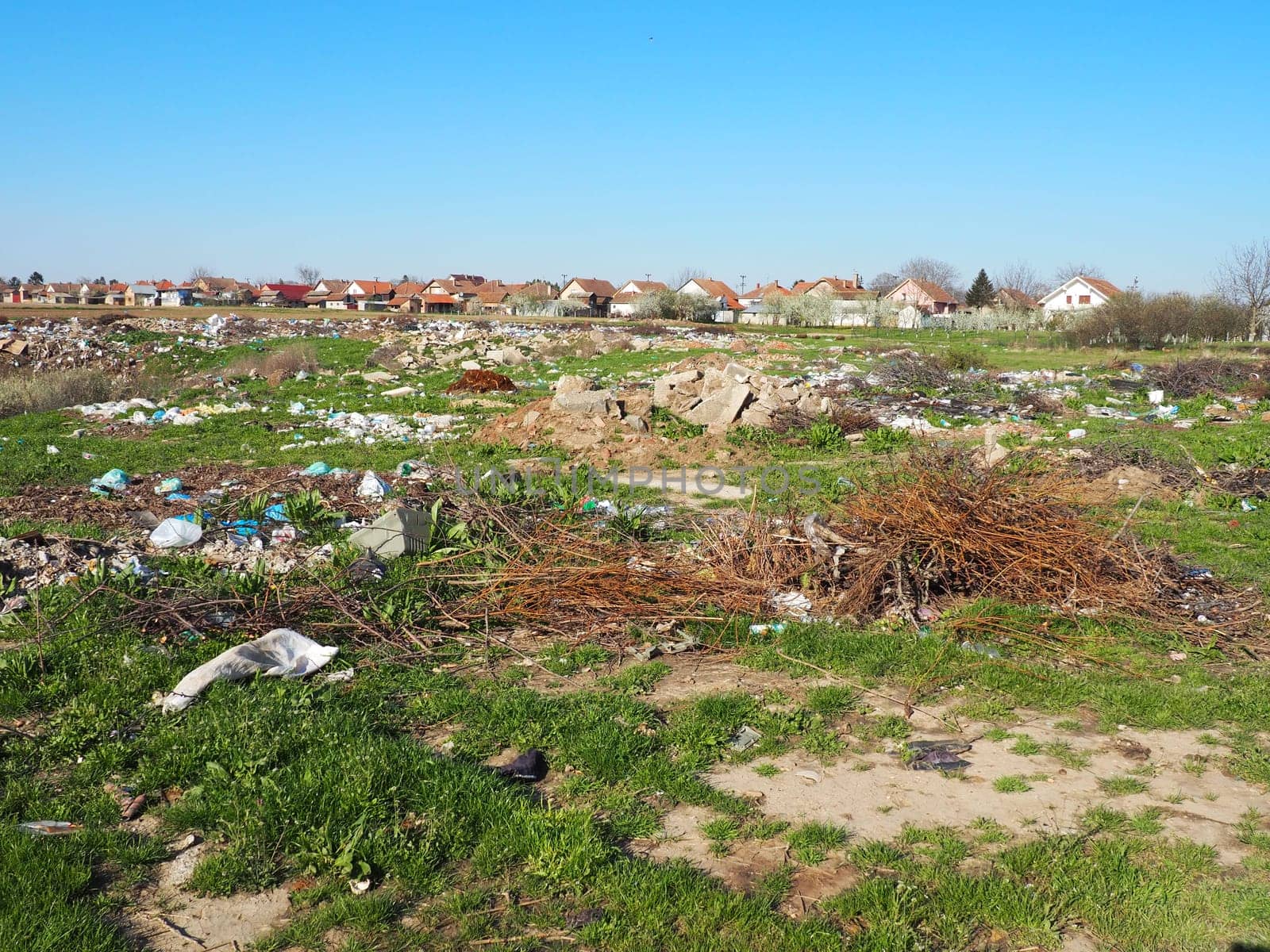 garbage dump near the village. Chaotic unofficial dump. Plastic, bags, paper, glass, biological waste. Green grass next to dirt. Ecological catastrophy
