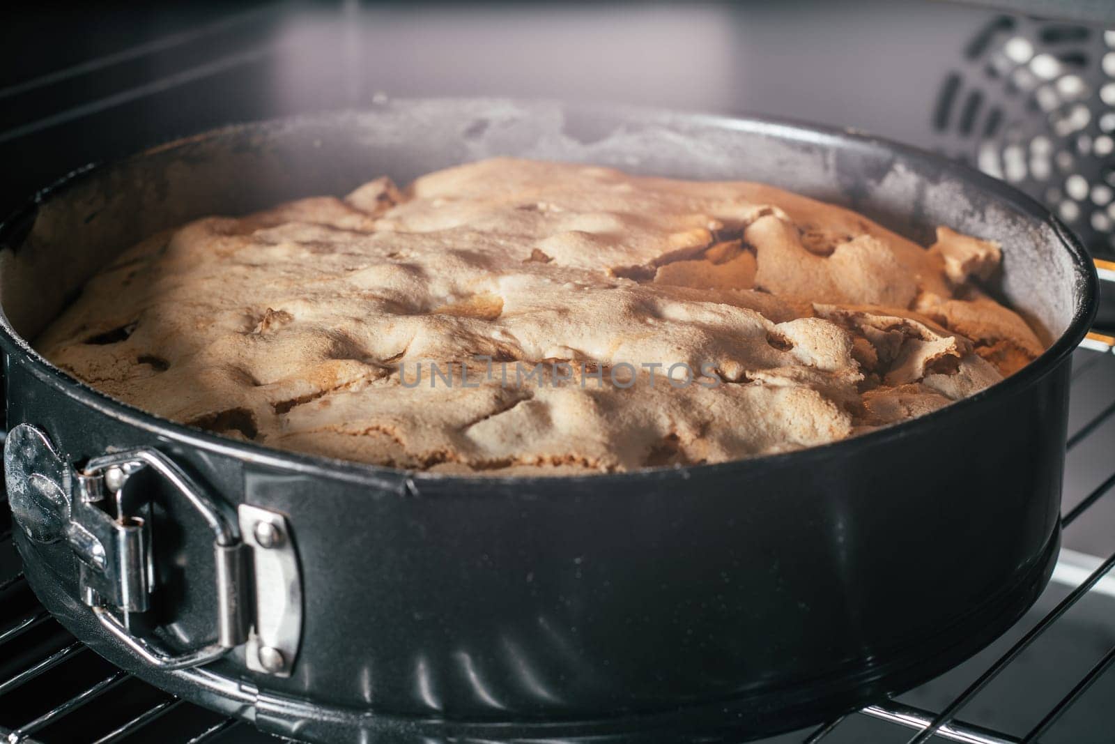 Baking dish with apple pie stands in black oven. Homemade seasonal bakery. Cooking in process