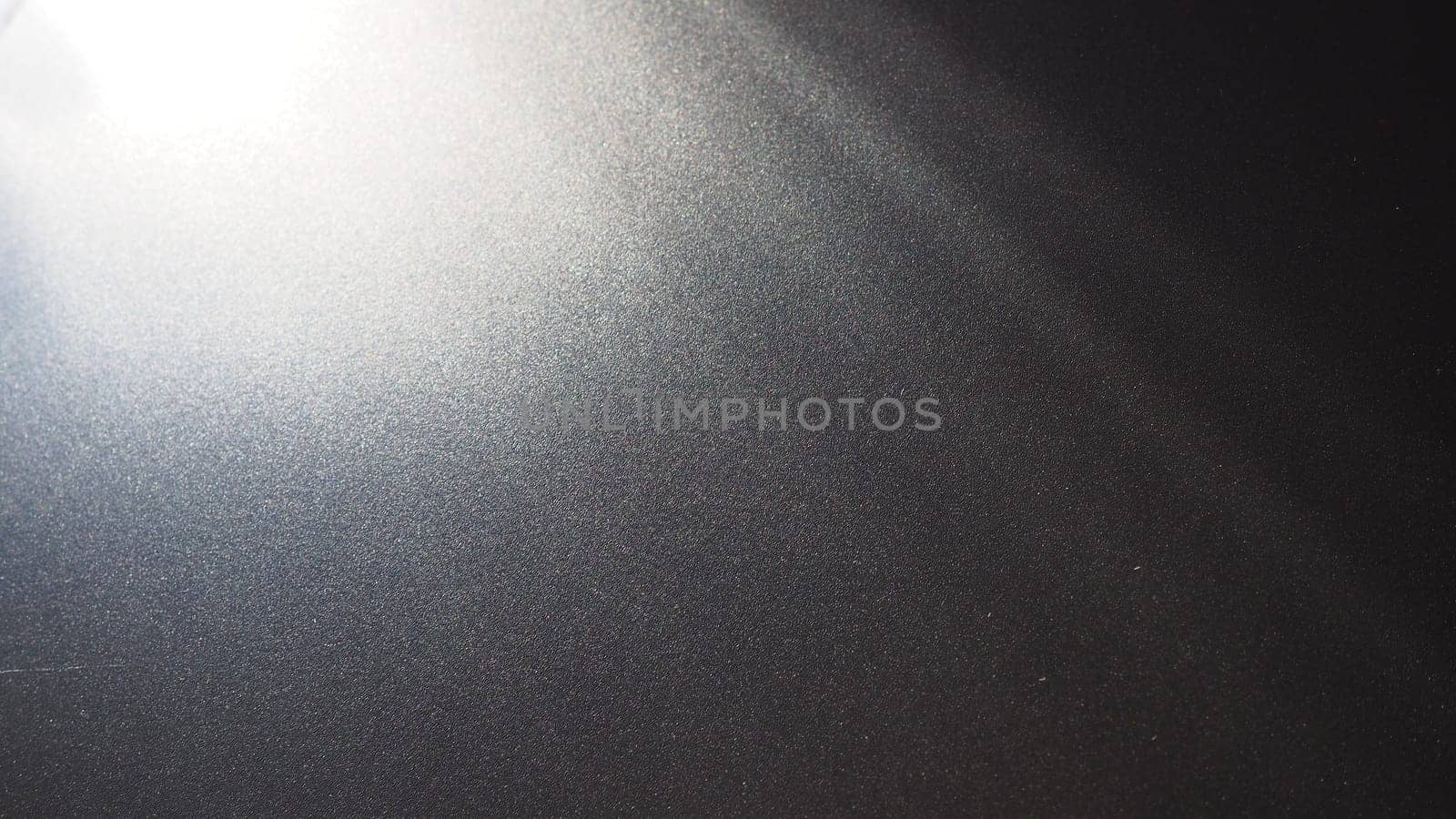 White bokeh and beam on a black background. Blurred glow from above on a dark surface. Night or space theme. Bokeh for the holiday. Abstract background. Glare, ray and light shine from above