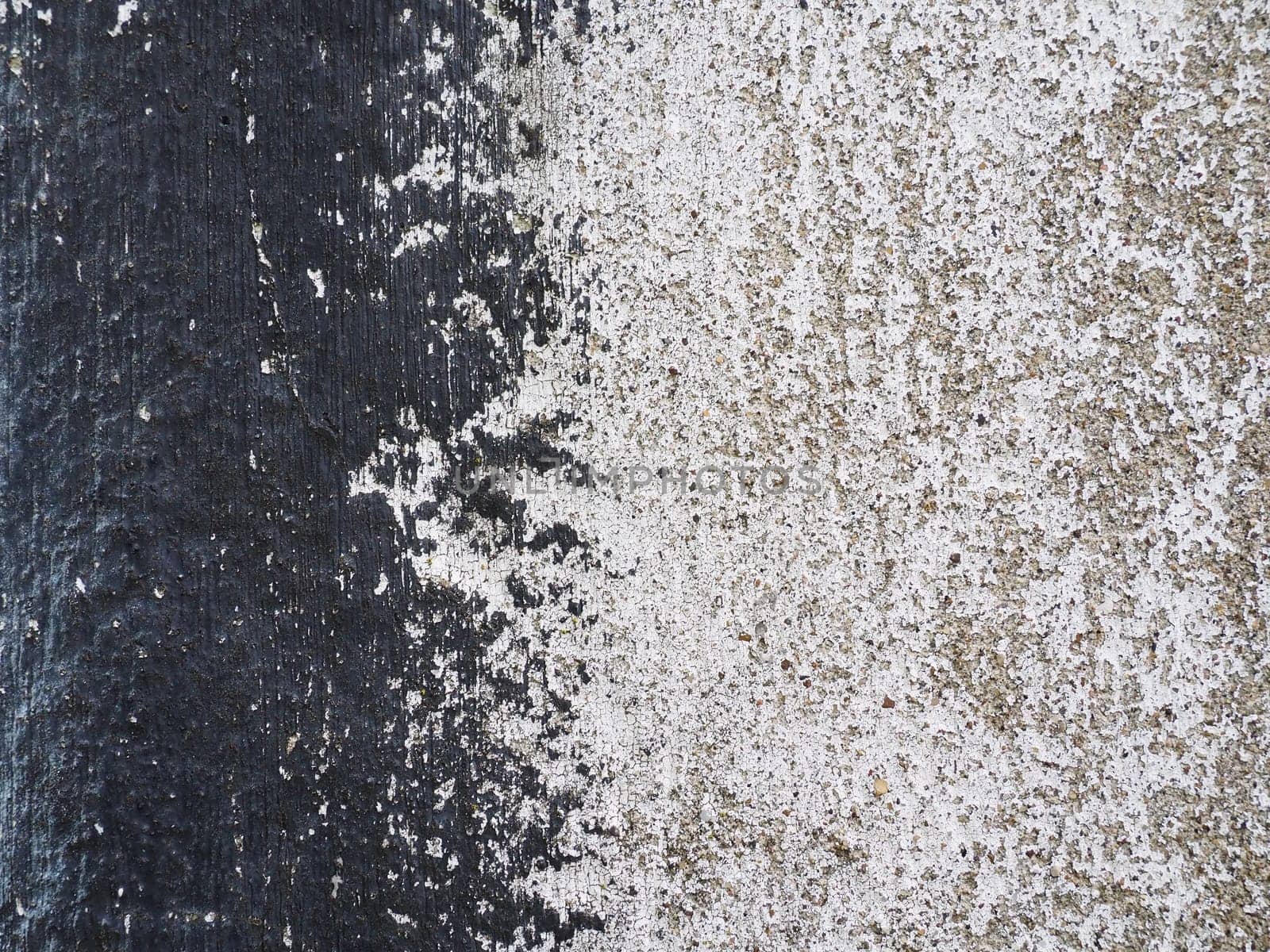 Concrete wall with black and white stripe of paint. Carelessly brushed parts, translucent gray plaster through the applied oil paint. Grunge background with empty space. Copy space.