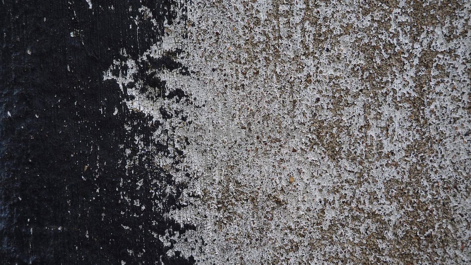 Concrete wall with black and white stripe of paint. Carelessly brushed parts, translucent gray plaster through the applied oil paint. Grunge background with empty space. Copy space.