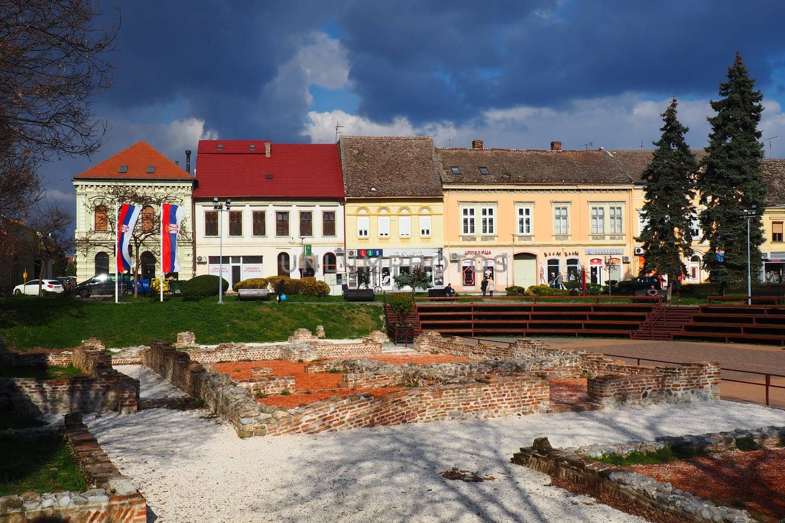 Sremska Mitrovica, Serbia, March 16, 2023 Zitni trg historical square. Ancient multi-colored buildings and excavations of Roman times. Cultural heritage. Dramatic sky. Excavations of Roman chambers