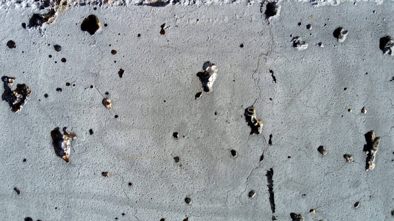 Concrete wall with concentric damage of large radius. Potholes, tubercles and defects. Grey colour. Planet surface concept. Concrete wall with a worn surface, potholes, bulges and small spots