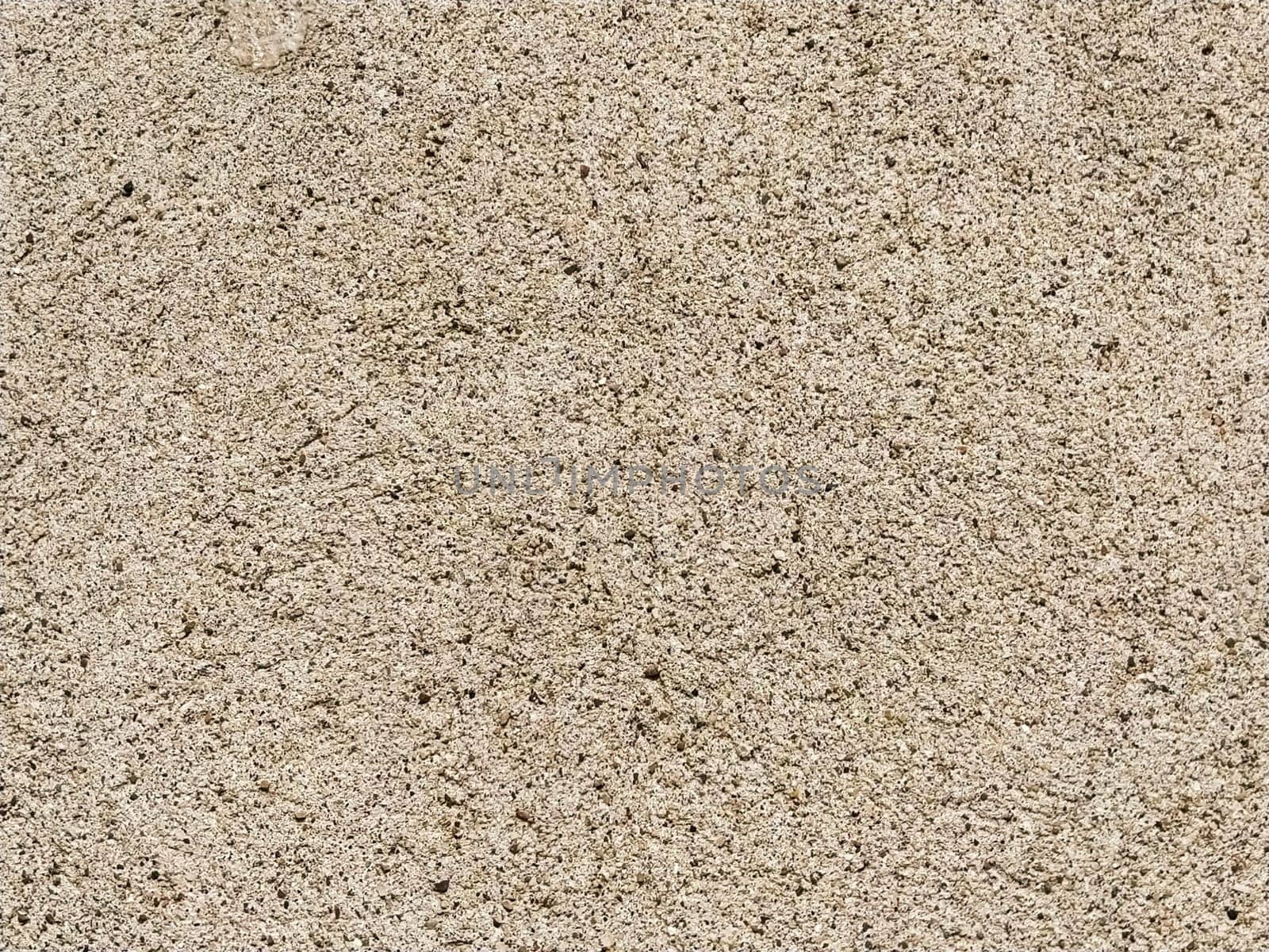 Concrete surface with multi-colored blotches of small stones. Light beige tone. Wall of a building or concrete slab. Close-up. Pockmarked cement surface. Interior or exterior finish option