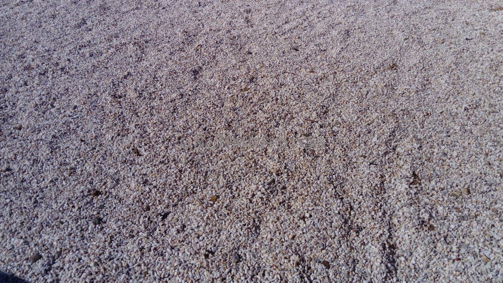 small pebbles or decorative gravel. Natural daylight. The texture of the stone with a rough surface. Pebble beach.