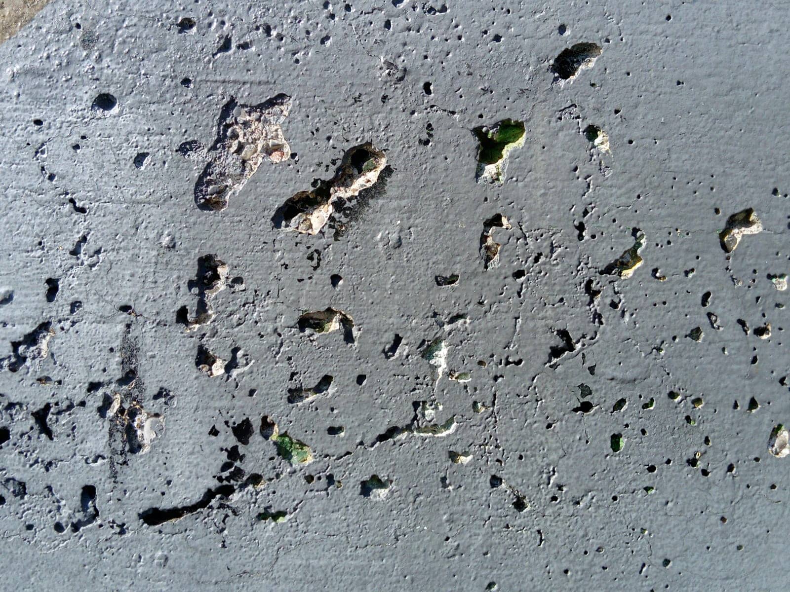 Concrete wall with concentric damage of large radius. Potholes, tubercles and defects. Grey colour. Planet surface concept. Concrete wall with a worn surface, potholes, bulges and small spots