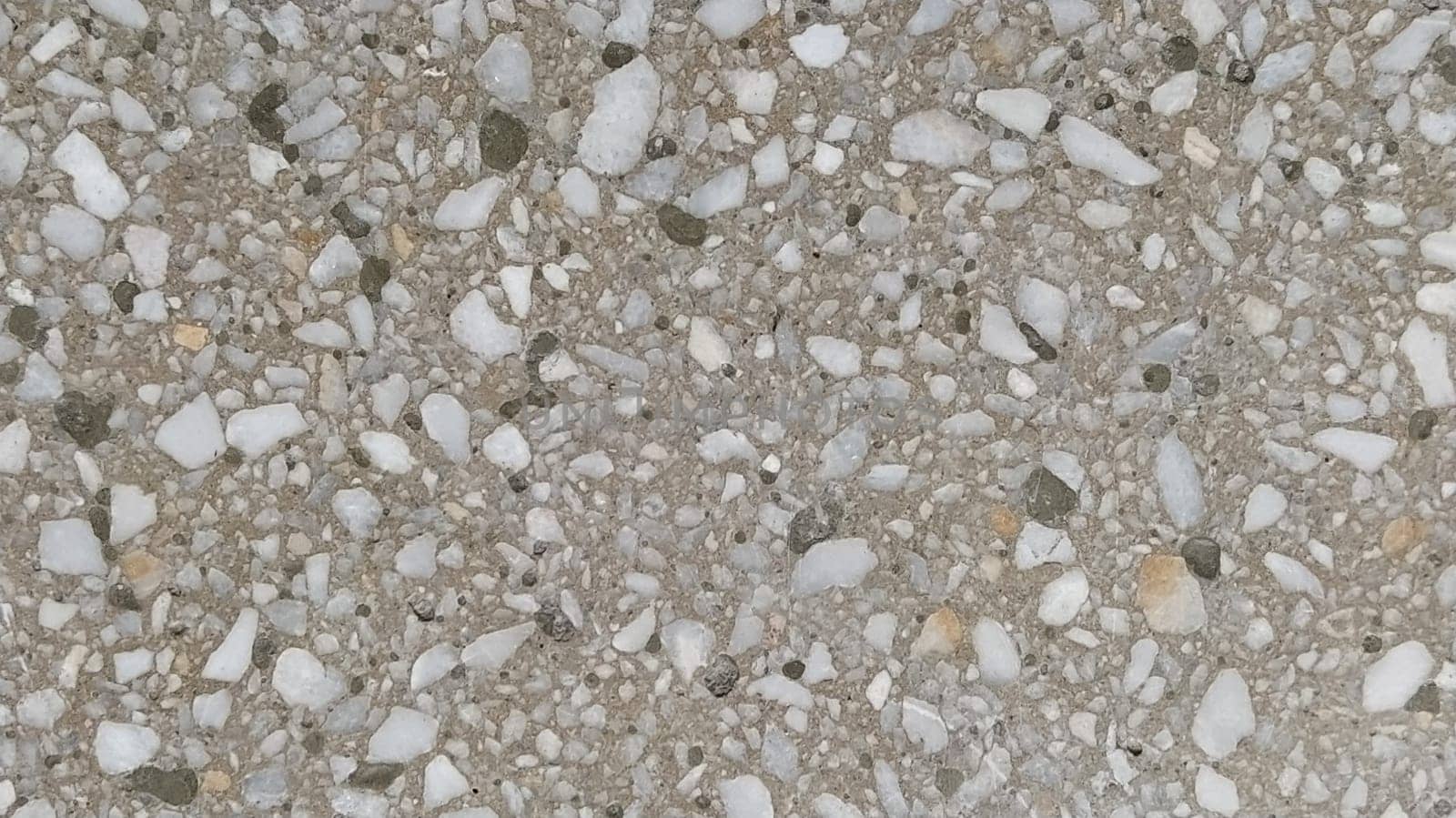 Concrete surface with multi-colored blotches of small stones. Light beige tone. Wall of a building or concrete slab. Close-up. Pockmarked cement surface. Interior or exterior finish option.