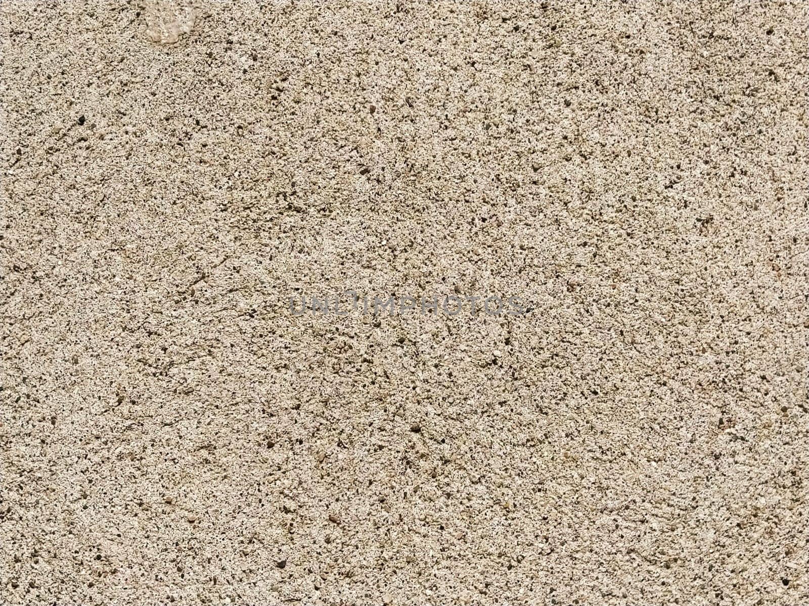 Concrete surface with multi-colored blotches of small stones. Light beige tone. Wall of a building or concrete slab. Close-up. Pockmarked cement surface. Interior or exterior finish option