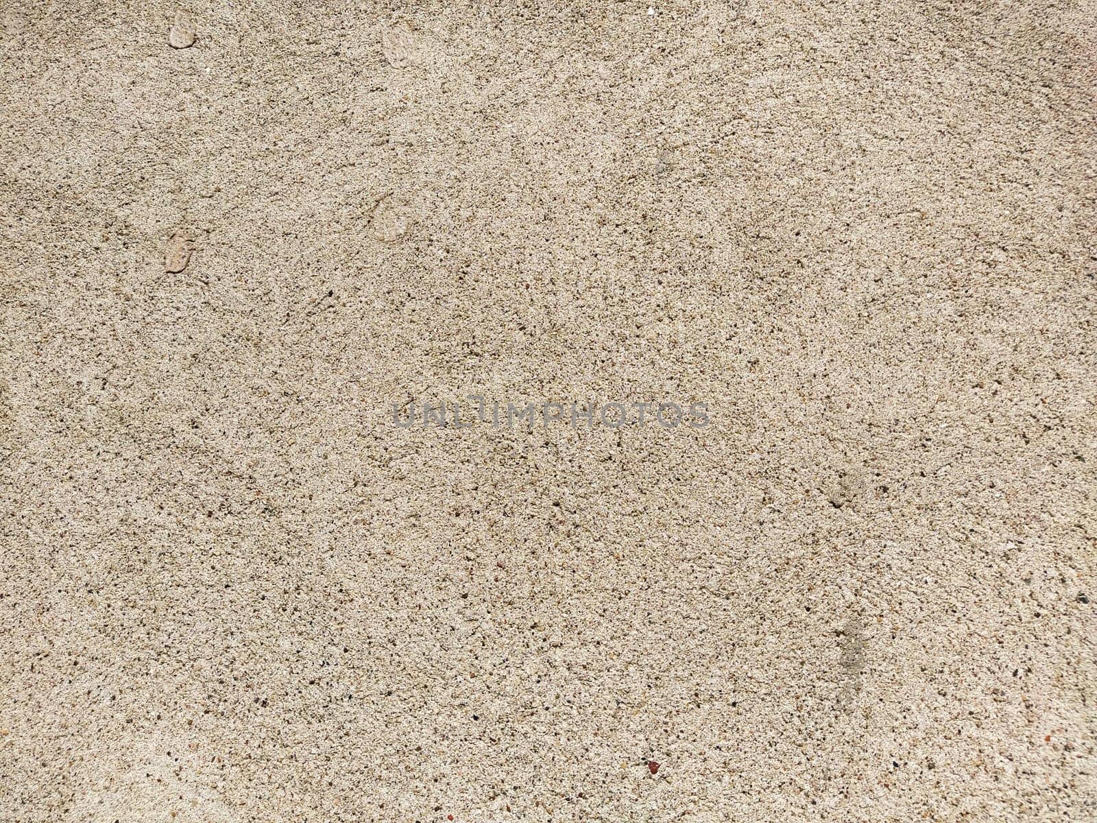 Concrete surface with multi-colored blotches of small stones. Light beige tone. Wall of a building or concrete slab. Close-up. Pockmarked cement surface. Interior or exterior finish option.