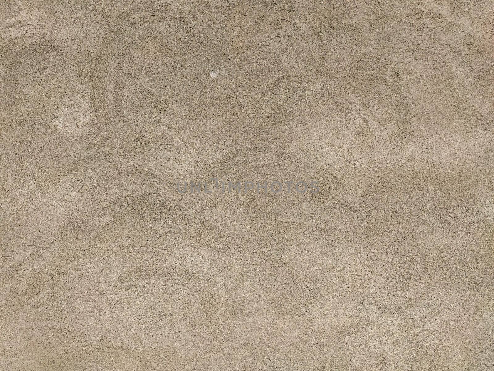 Concrete surface with multi-colored blotches of small stones. Light beige tone. Wall of a building or concrete slab. Close-up. Pockmarked cement surface. Interior or exterior finish option