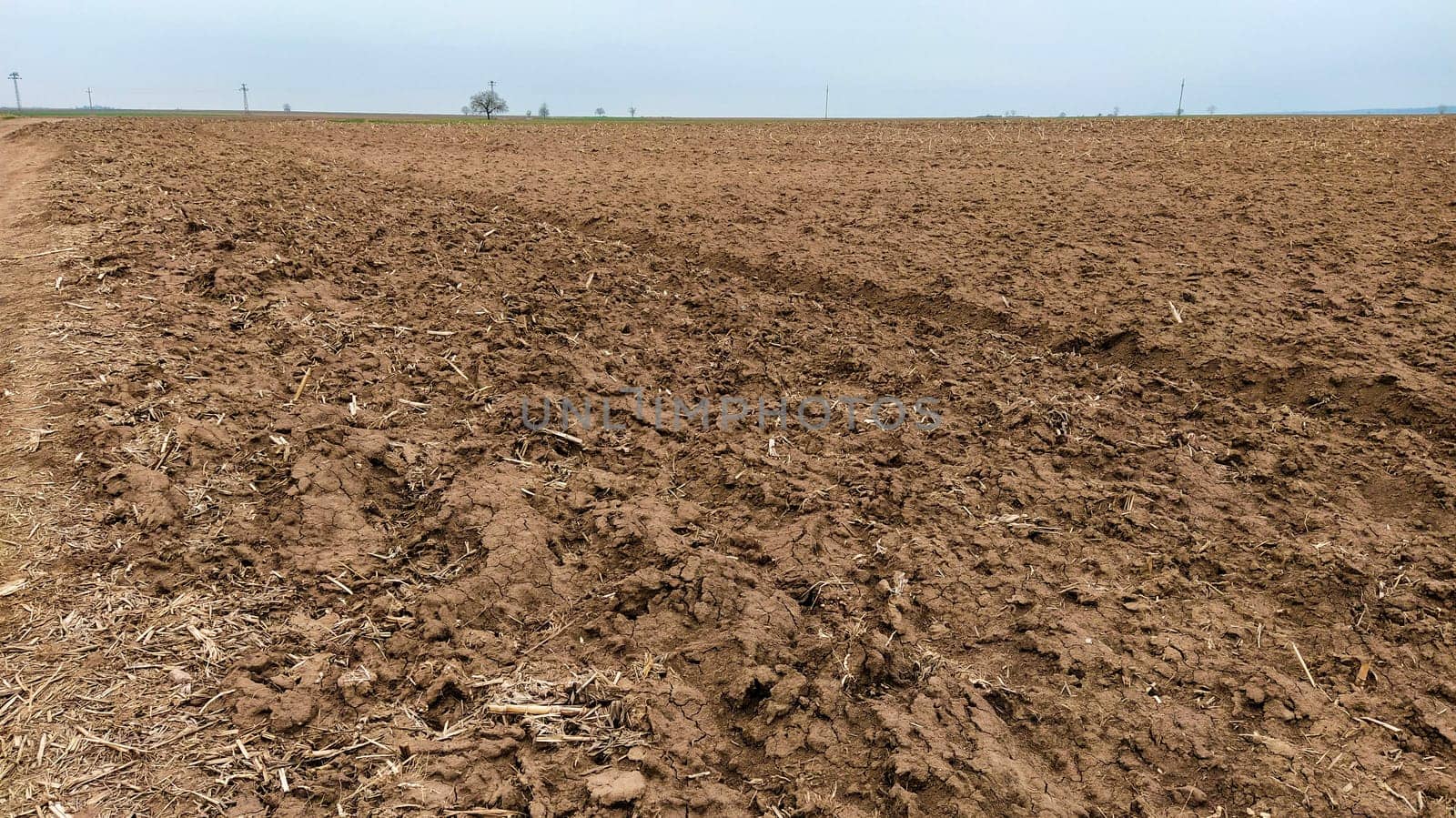 Freshly plowed field. Arable land with fertile soil for planting wheat. Rural landscape in Serbia, Balkans, namely Fruska Gora from Sremska Mitrovica. Furrows and pits. Preparatory agricultural work.