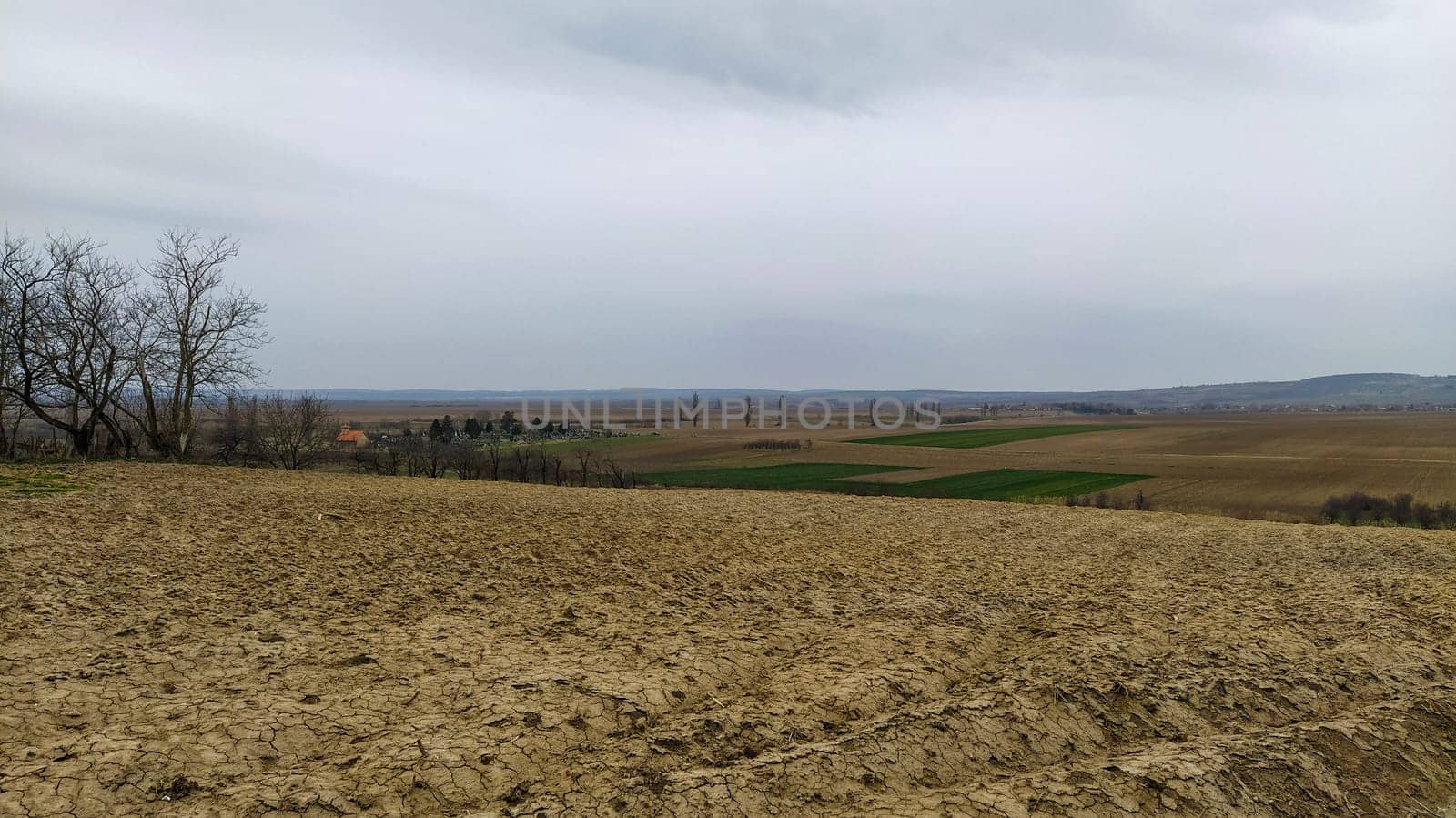 Freshly plowed field. Arable land with fertile soil for planting wheat. Rural landscape in Serbia, Balkans, namely Fruska Gora from Sremska Mitrovica. Furrows and pits. Preparatory agricultural work.
