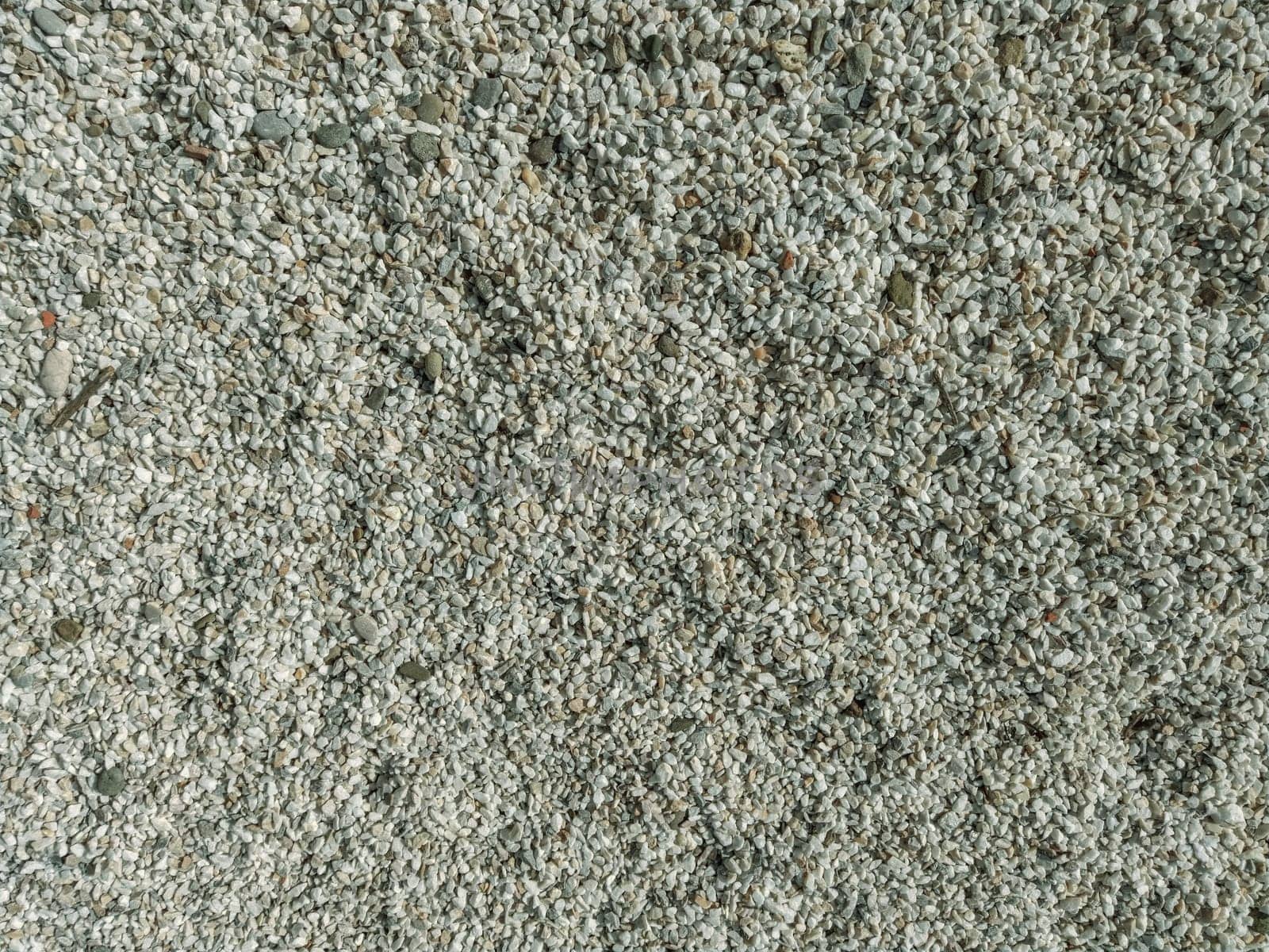 White small pebbles or decorative gravel. Natural daylight. The texture of the stone with a rough surface. Pebble beach.