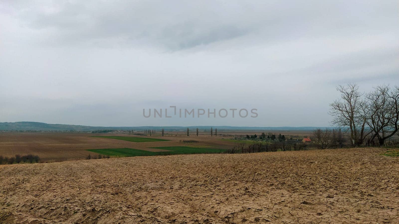 Freshly plowed field. Arable land with fertile soil for planting wheat. Rural landscape in Serbia, Balkans, namely Fruska Gora from Sremska Mitrovica. Furrows and pits. Preparatory agricultural work.