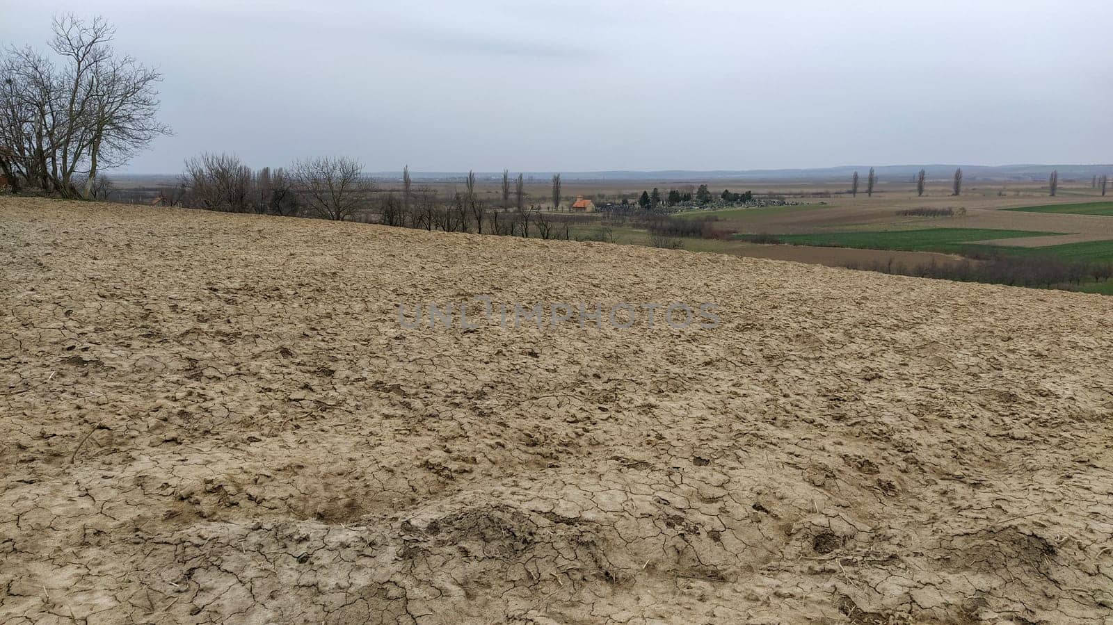 Freshly plowed field. Arable land with fertile soil for planting wheat. Rural landscape in Serbia, Balkans, namely Fruska Gora from Sremska Mitrovica. Furrows and pits. Preparatory agricultural work.