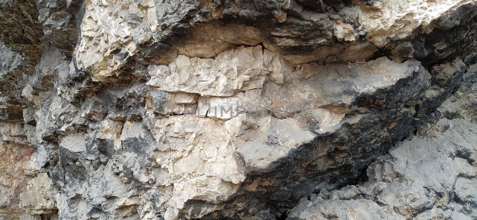 stone rock closeup in Sarajevo, Bosnia and Herzegovina. Ancient frozen lava. Layers and strata of rocks. Mountain after a guided explosion to lay the road. Texture of the stone. Gray and beige colors.
