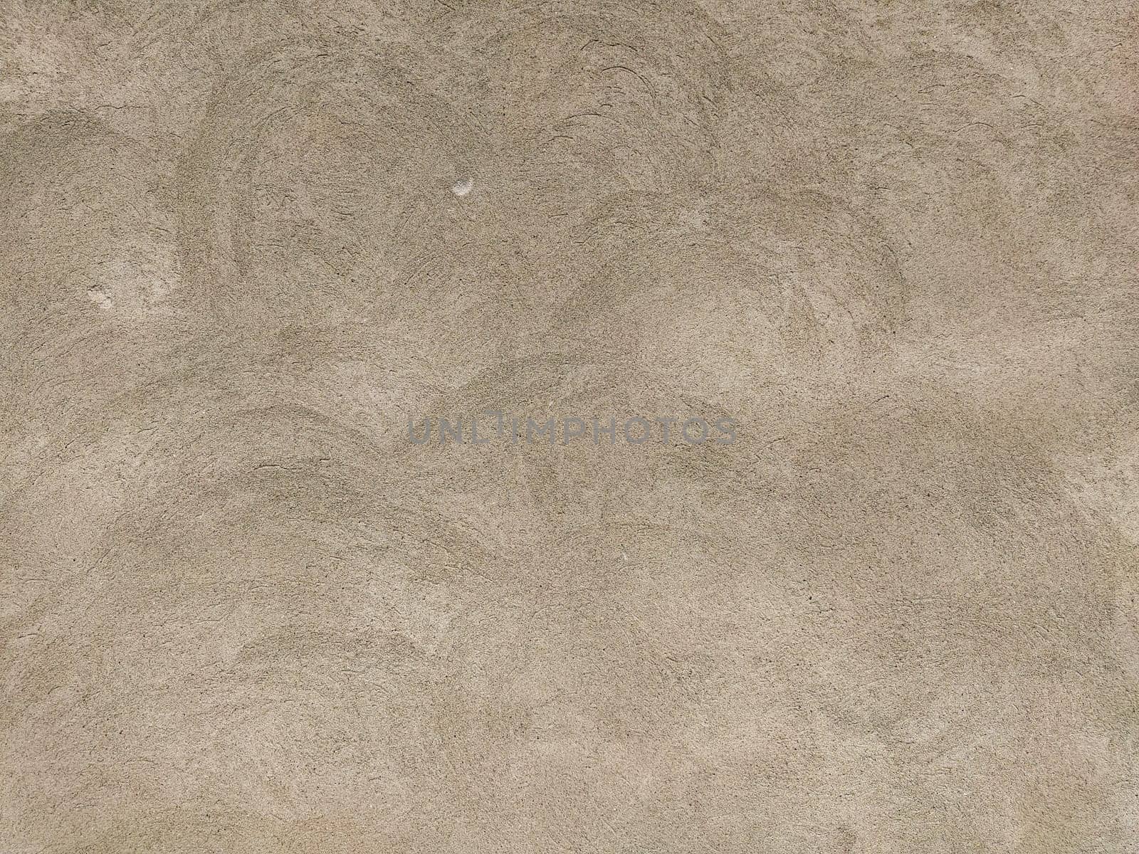 Concrete surface with multi-colored blotches of small stones. Light beige tone. Wall of a building or concrete slab. Close-up. Pockmarked cement surface.