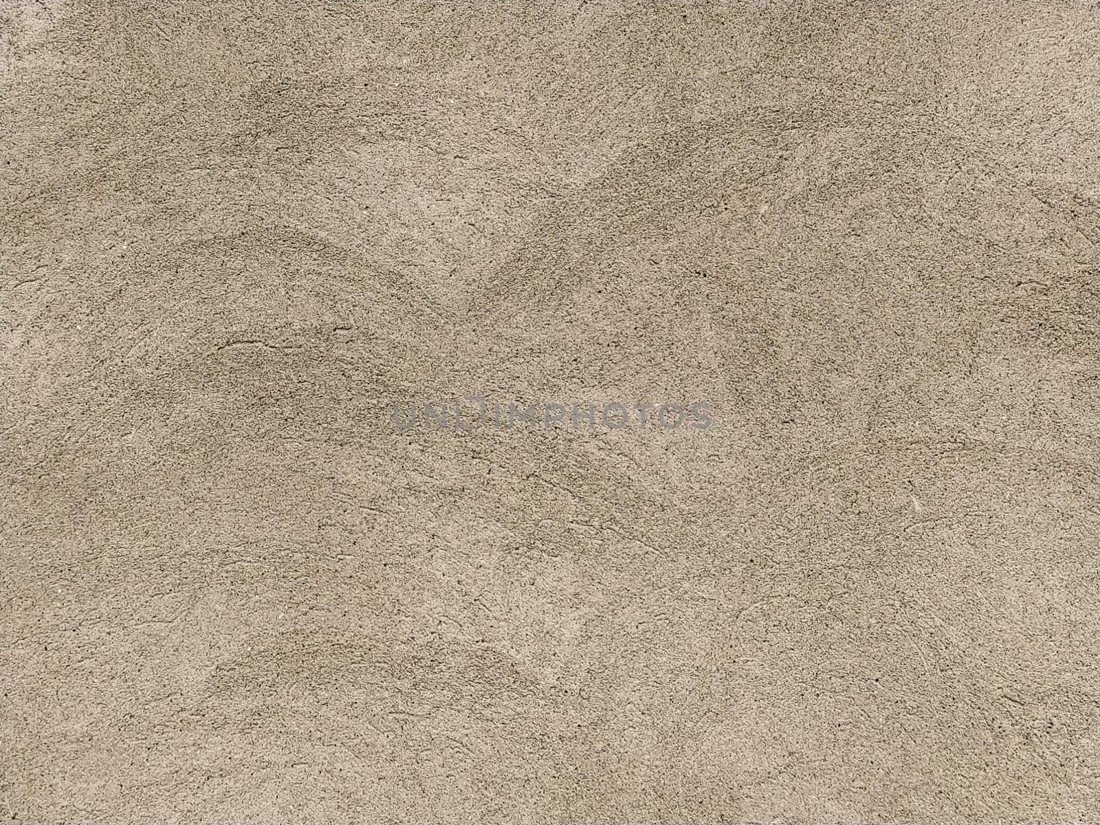 Concrete surface with multi-colored blotches of small stones. Light beige tone. Wall of a building or concrete slab. Close-up. Pockmarked cement surface. Interior or exterior finish option