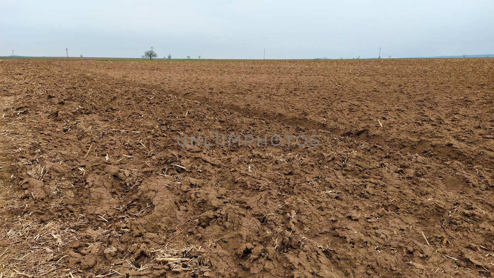 Freshly plowed field. Arable land with fertile soil for planting wheat. Rural landscape in Serbia, Balkans, namely Fruska Gora from Sremska Mitrovica. Furrows and pits. Preparatory agricultural work.
