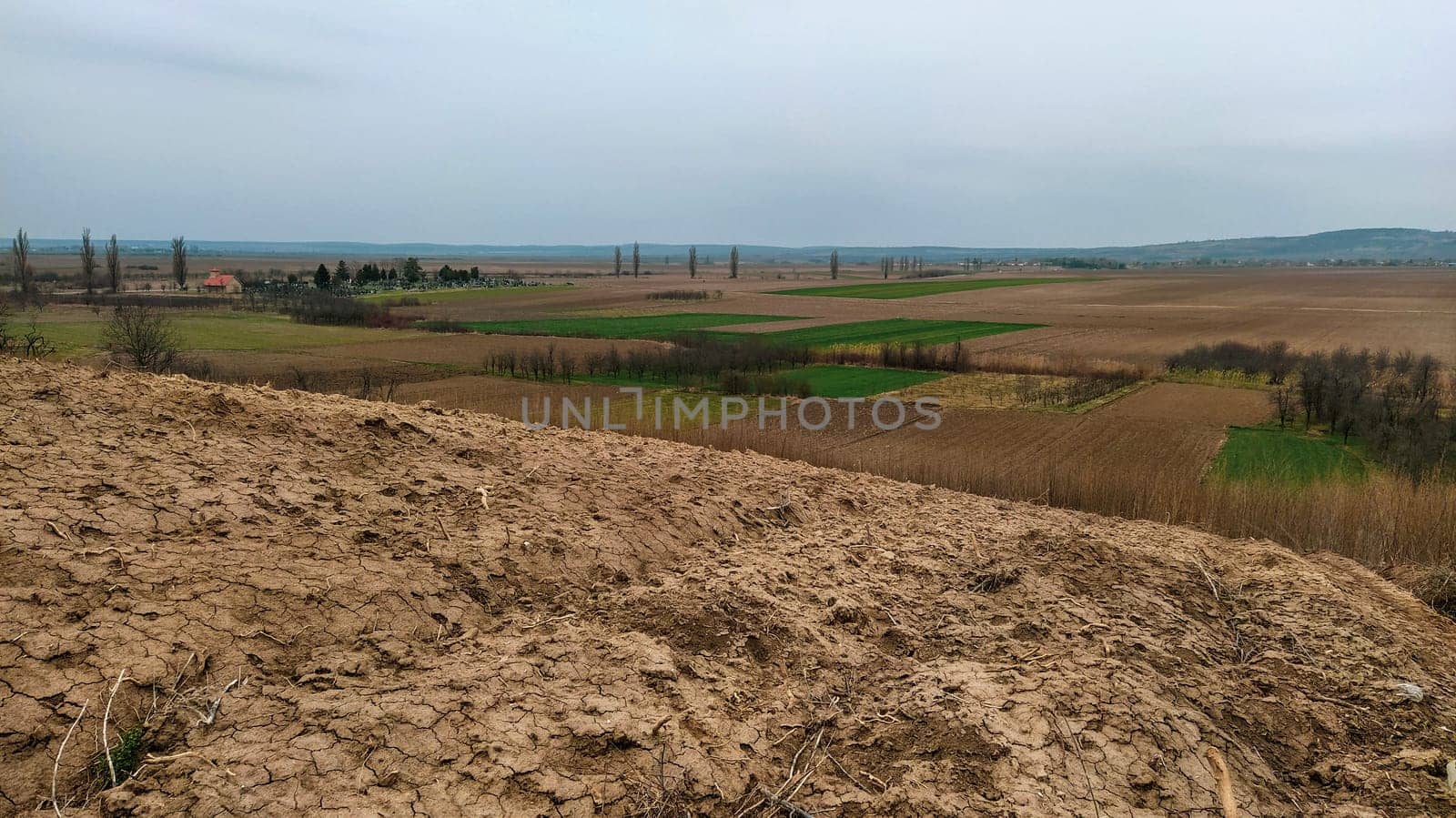 Freshly plowed field. Arable land with fertile soil for planting wheat. Rural landscape in Serbia, Balkans, namely Fruska Gora from Sremska Mitrovica. Furrows and pits. Preparatory agricultural work.