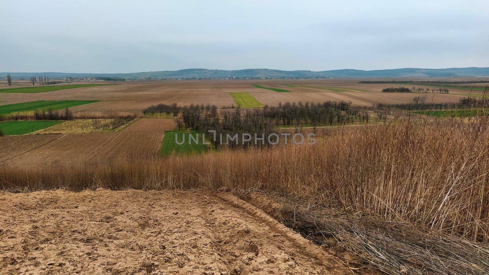 Freshly plowed field. Arable land with fertile soil for planting wheat. Rural landscape in Serbia, Balkans, namely Fruska Gora from Sremska Mitrovica. Furrows and pits. Preparatory agricultural work.