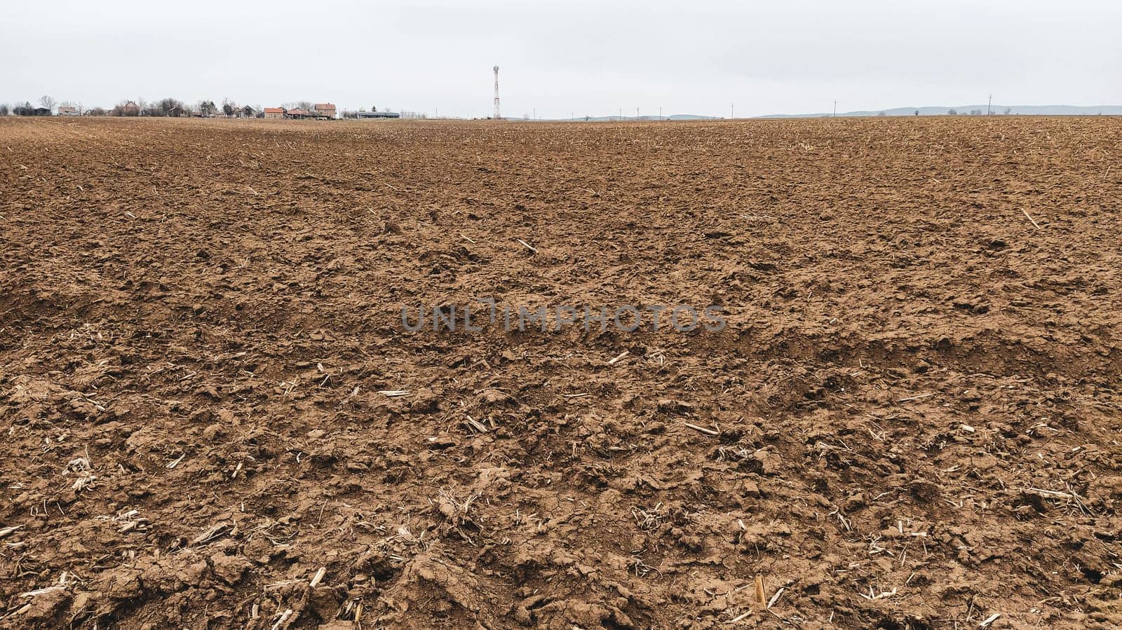 Freshly plowed field. Arable land with fertile soil for planting wheat. Rural landscape in Serbia, Balkans, namely Fruska Gora from Sremska Mitrovica. Furrows and pits. Preparatory agricultural work.