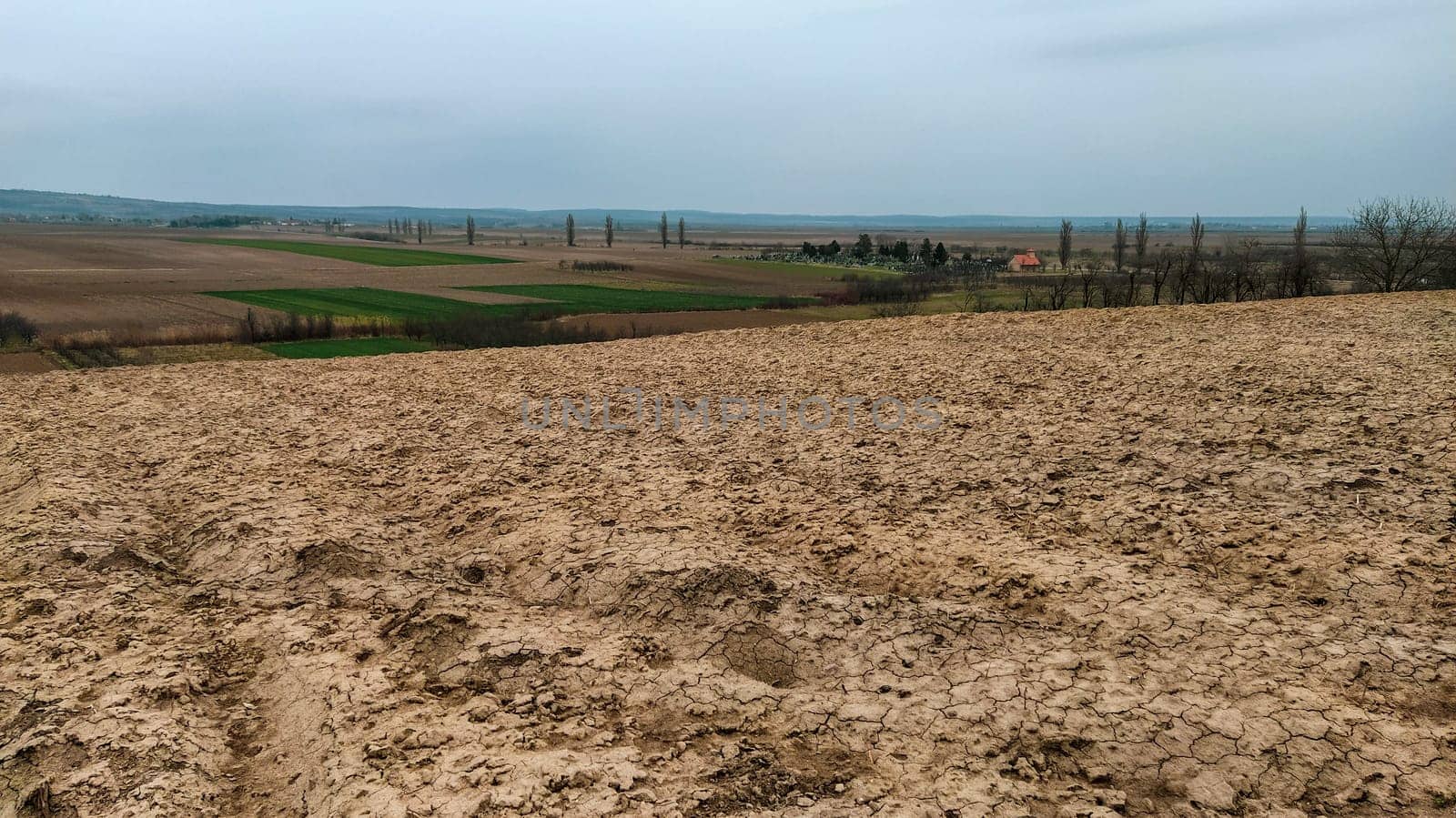 Freshly plowed field. Arable land with fertile soil for planting wheat. Rural landscape in Serbia, Balkans, namely Fruska Gora from Sremska Mitrovica. Furrows and pits. Preparatory agricultural work.