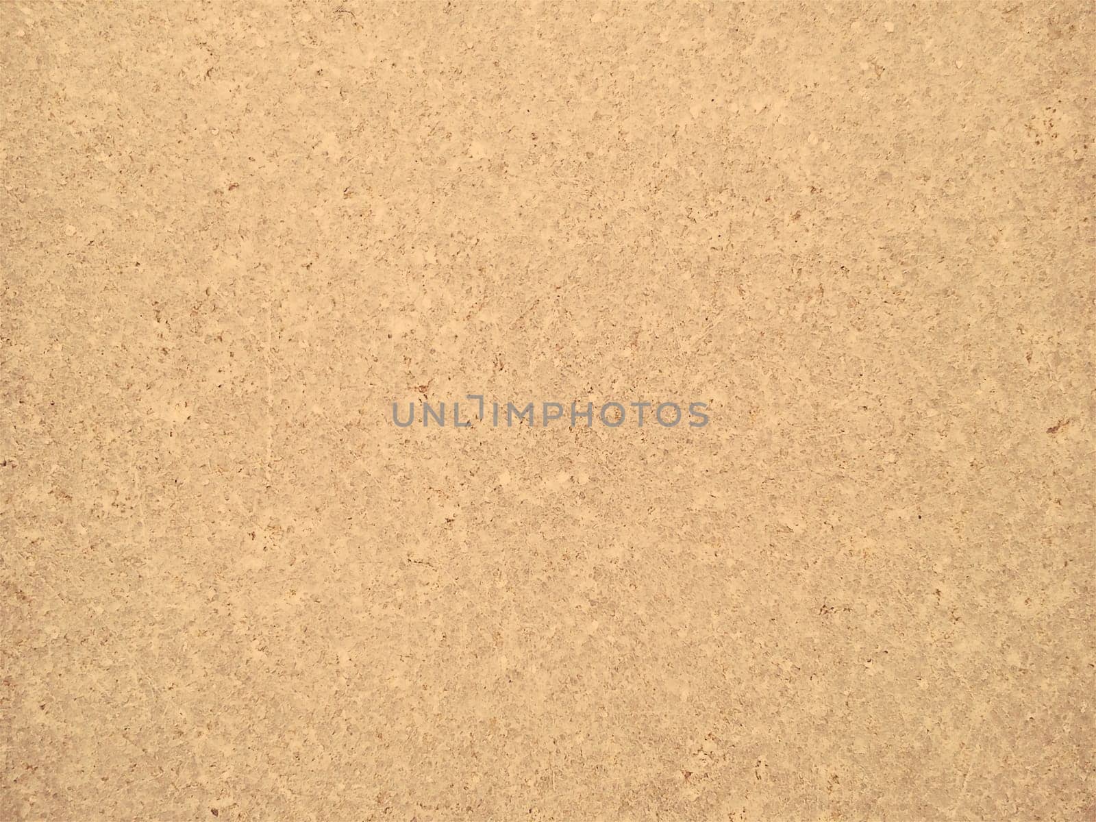 Granite is yellow-brown in color with small light and dark specks, uneven scratches. The texture of the stone. Warm colors and shades. Dim background.