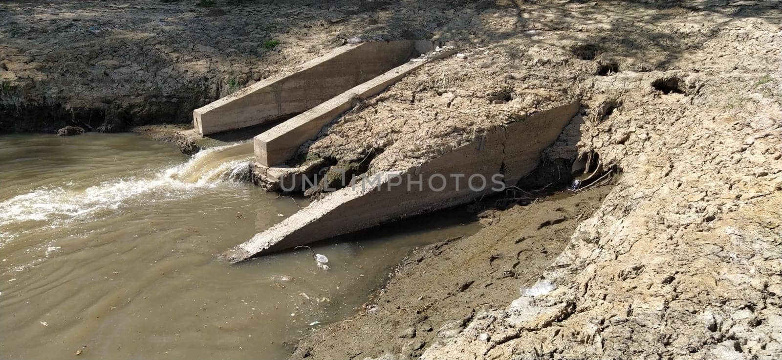 A large city drain drains sewage into a canal that flows into the river. Ecological problem. The concept of environmental protection and ecology. Concrete structure