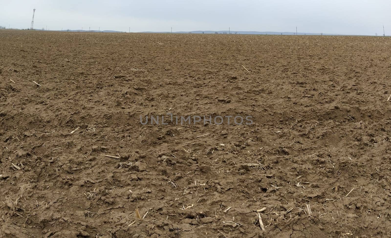 Plowed field. Arable land with fertile soil for planting crops. Rural landscape in Serbia, in the Balkans. Furrows and pits. Panorama.