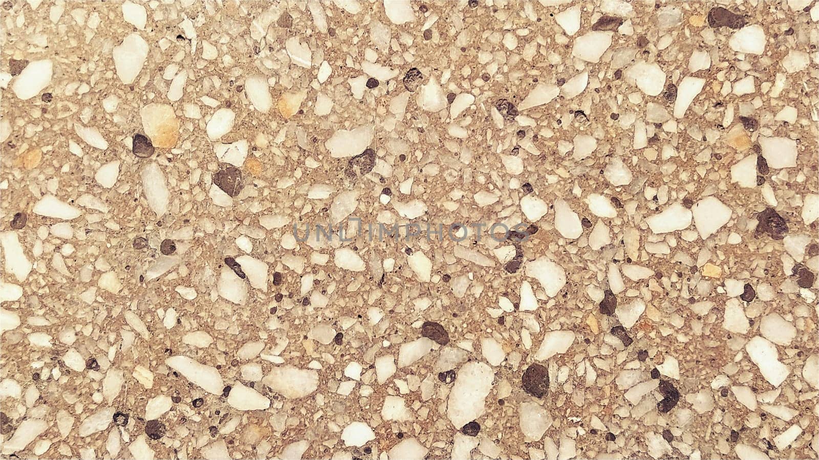 Concrete surface with multi-colored spots of small stones. Beige or orange tone. Wall of a building or concrete slab. Close-up. Spotty cement surface. Interior or exterior decoration.