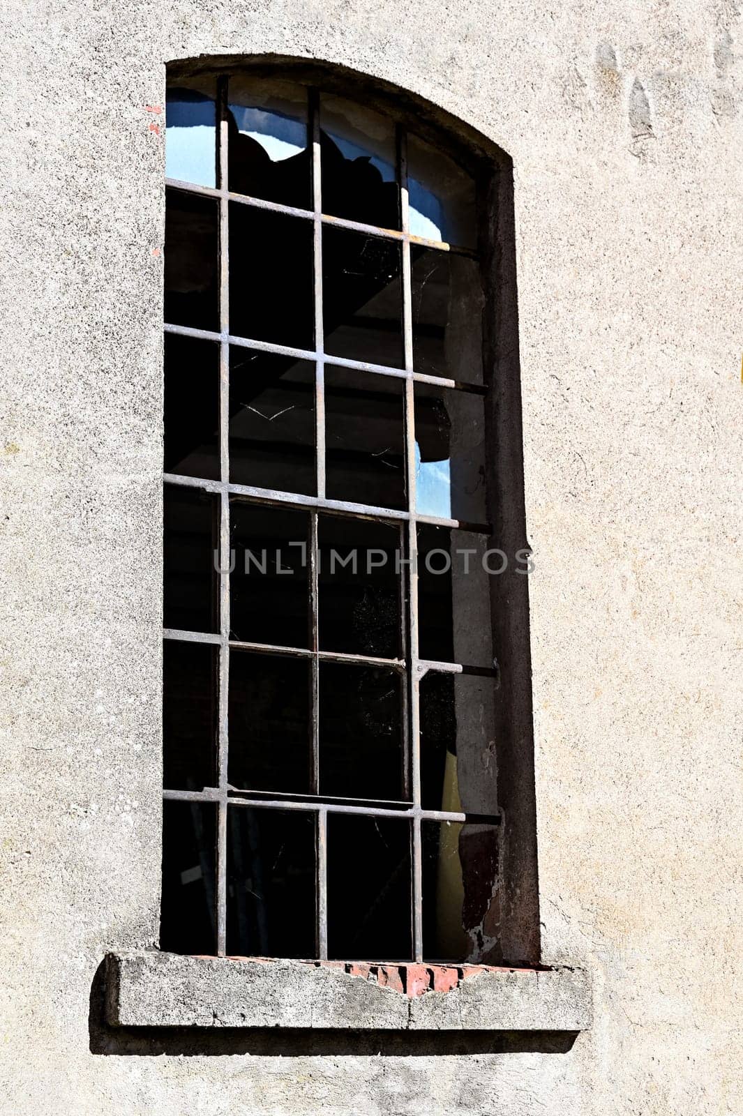 Window with metal bars and broken panes of glass in an old derelict building