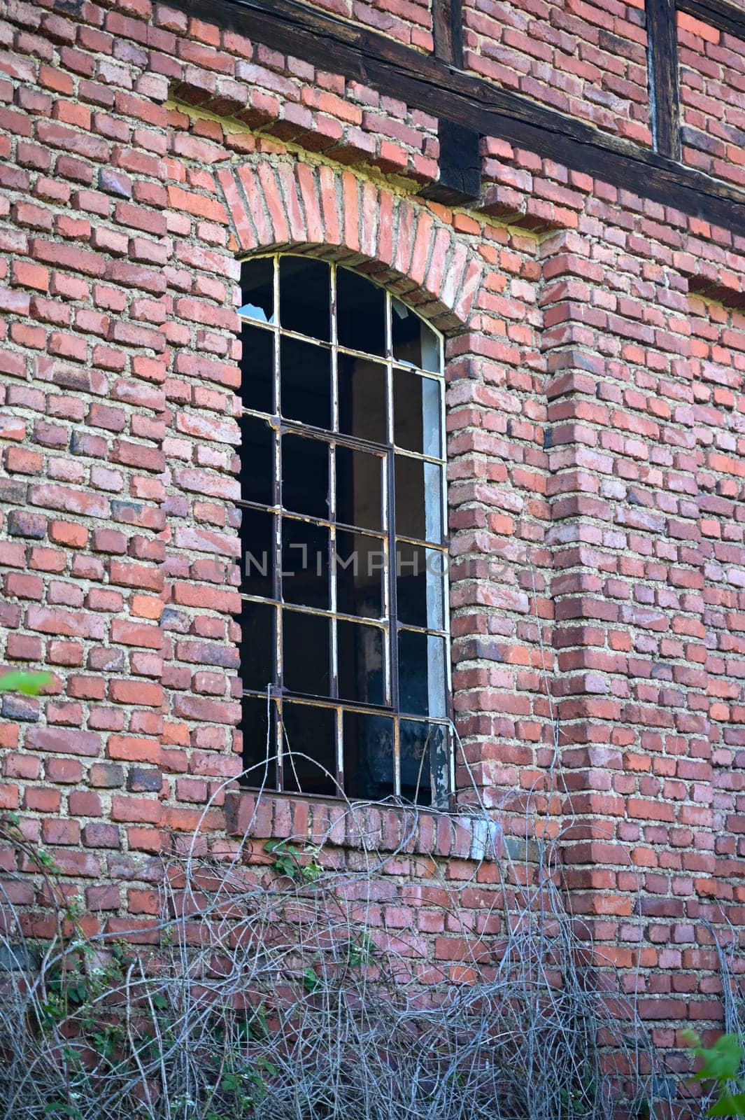 Window with metal bars and broken panes of glass in an old derelict building