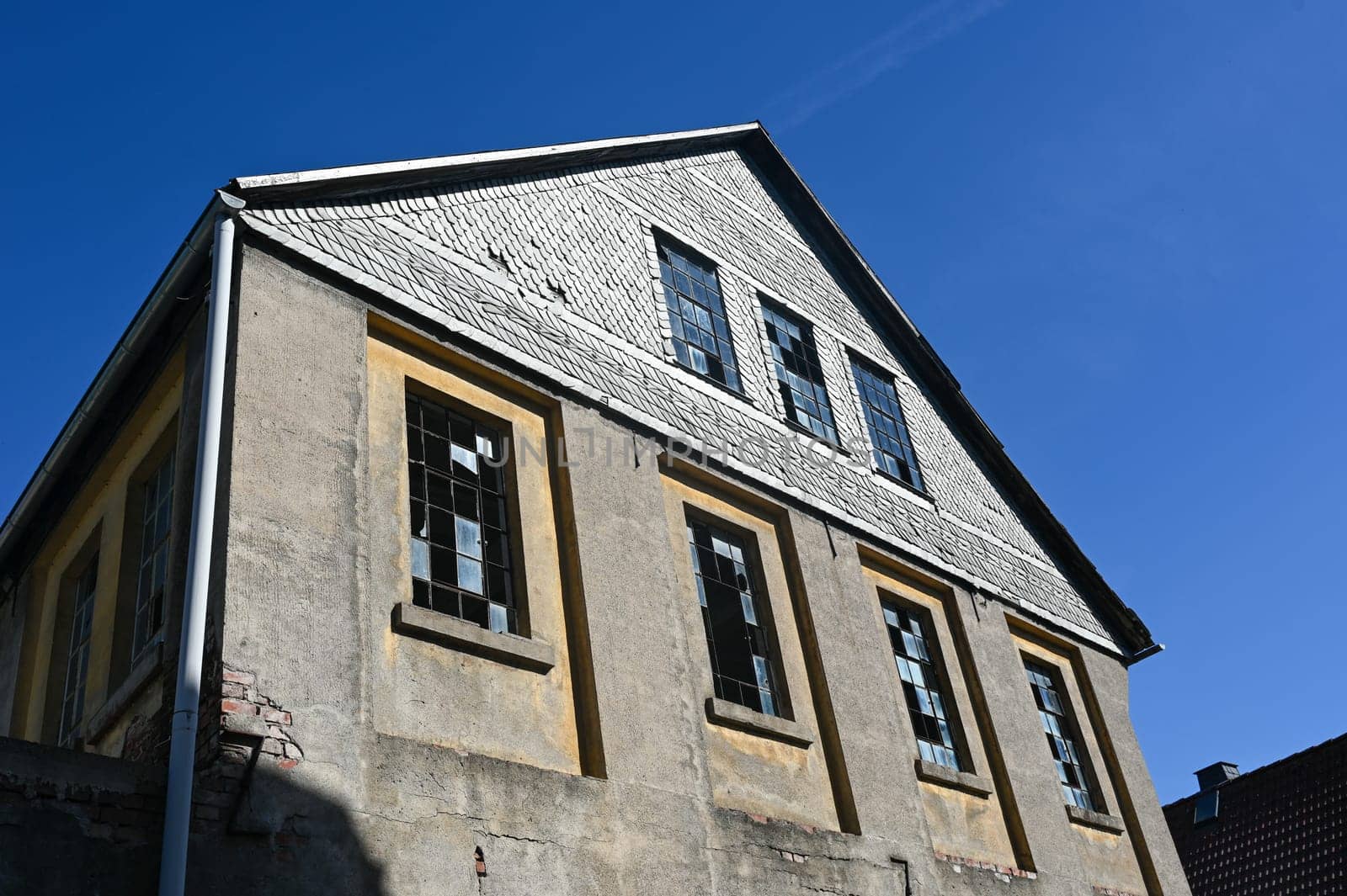 Facade of an old house with metal grille windows and broken glass panes in an old vacant building