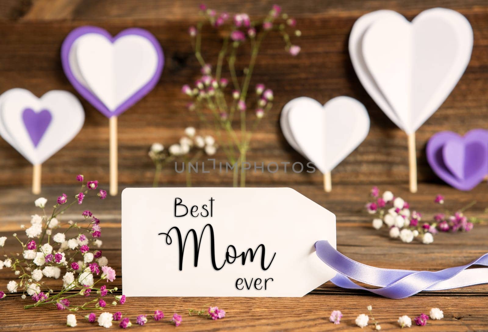 Label With English Text Welcome. Purple And Lilac Decoration And Spring Flower Arrangement. Heart Symbols With Wooden Background.