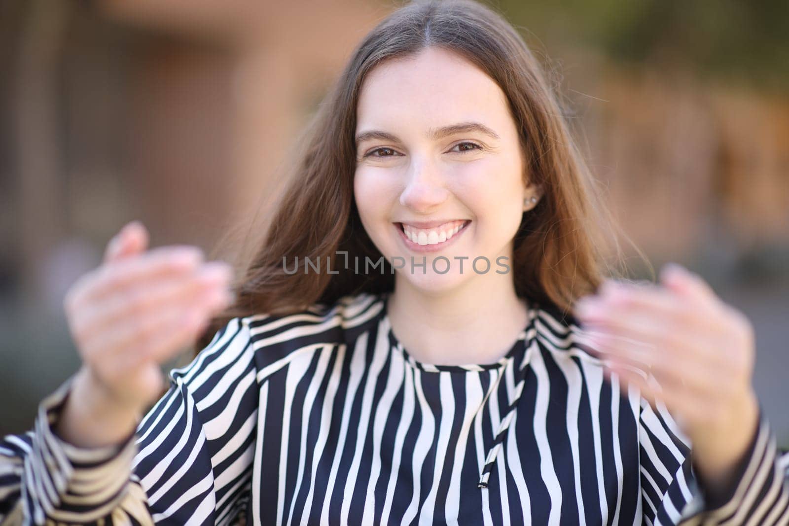 Front view portrait of an elegant woman gesturing come here in the street