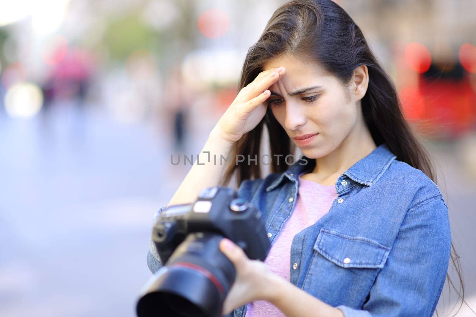 Worried photographer checking photoshoot results on camera in the street