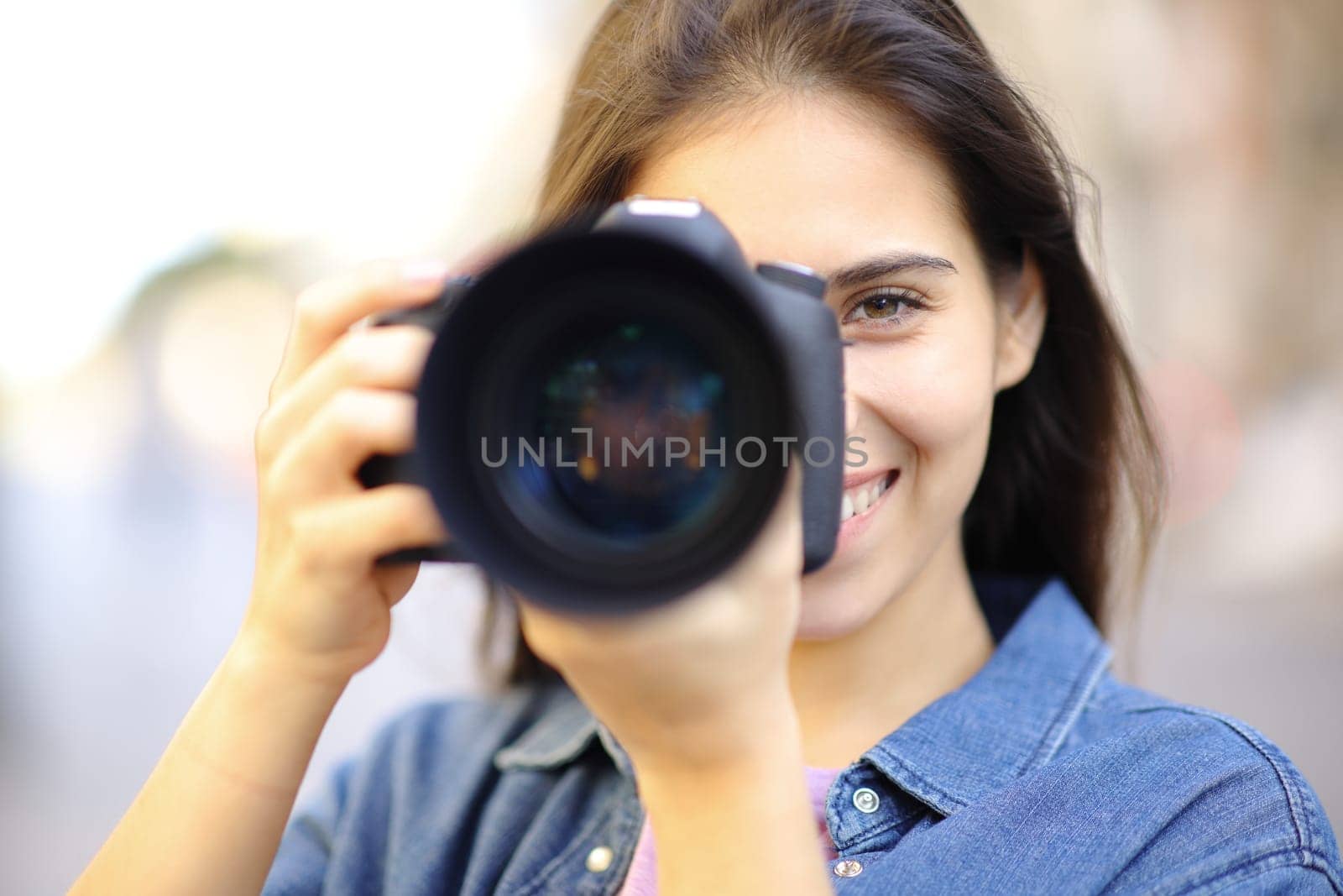 Front view portrait of a happy photographer taking photo of you