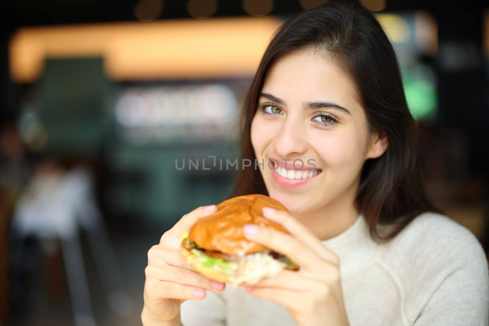 Happy woman ready to eat burguer in a restaurant looking at camera