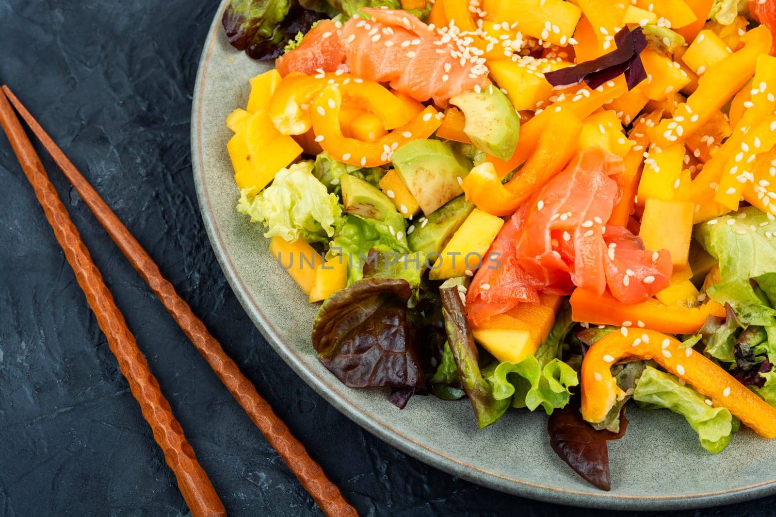 Asian salad with smoked salmon, mango, sesame and vegetables. Close up.