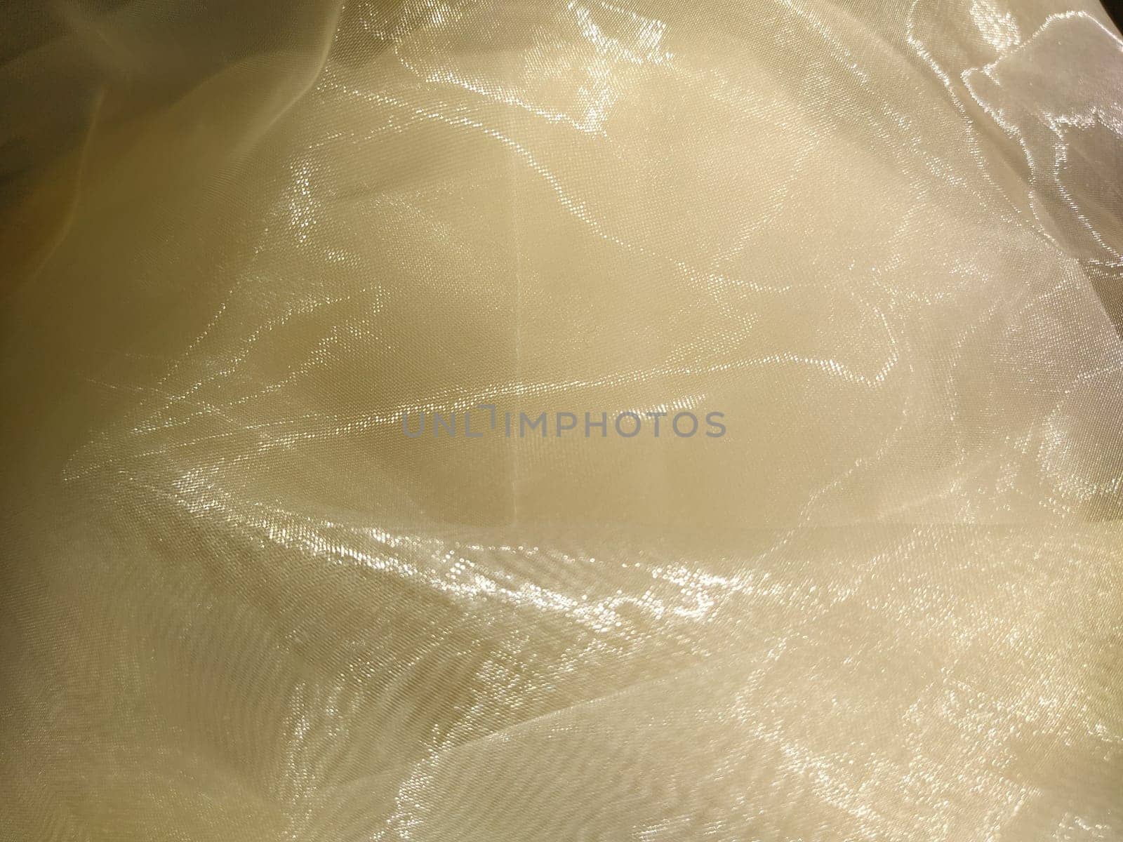 Organza in white and beige or champagne color close-up. Lightweight sheer tulle curtains under side lighting.
