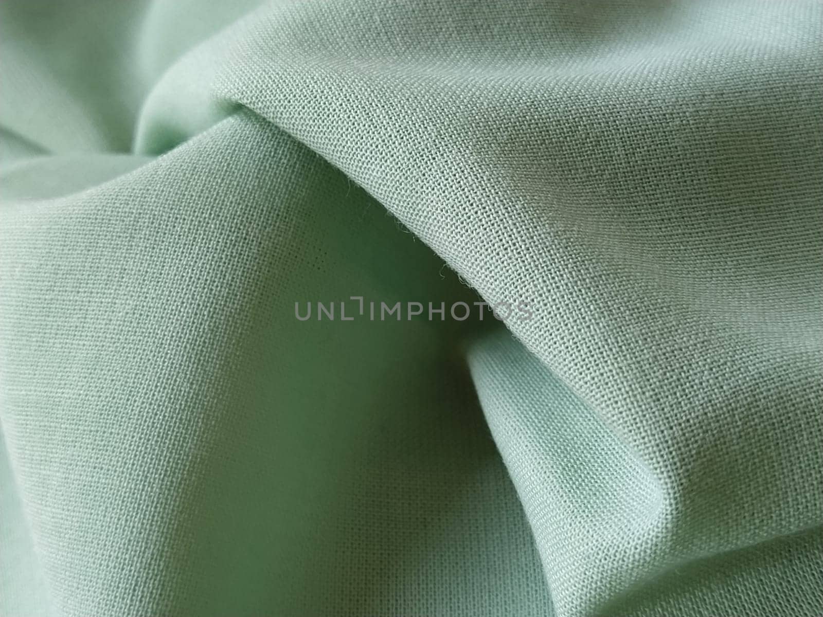 Close up of a woolen fabric of green color. Abstract canvas background, empty template. Thin natural fabric, wool or linen.