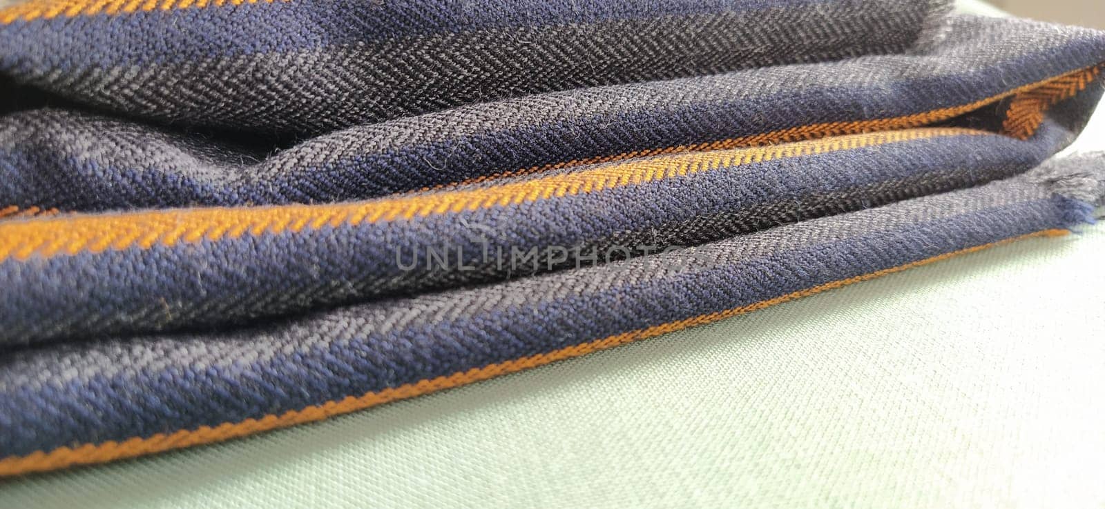 Light green and black-gray folded fabric with orange and dark blue stripes. Interior decoration. Dress fabrics in casual style. Dense material for indoor curtains and furniture finishing.
