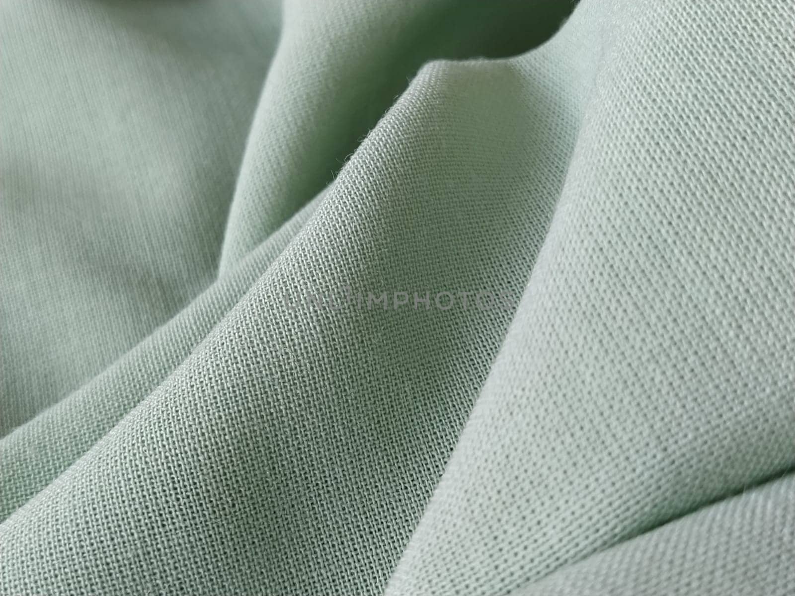 Close up of a woolen fabric of green color. Abstract canvas background, empty template. Thin natural fabric, wool or linen.