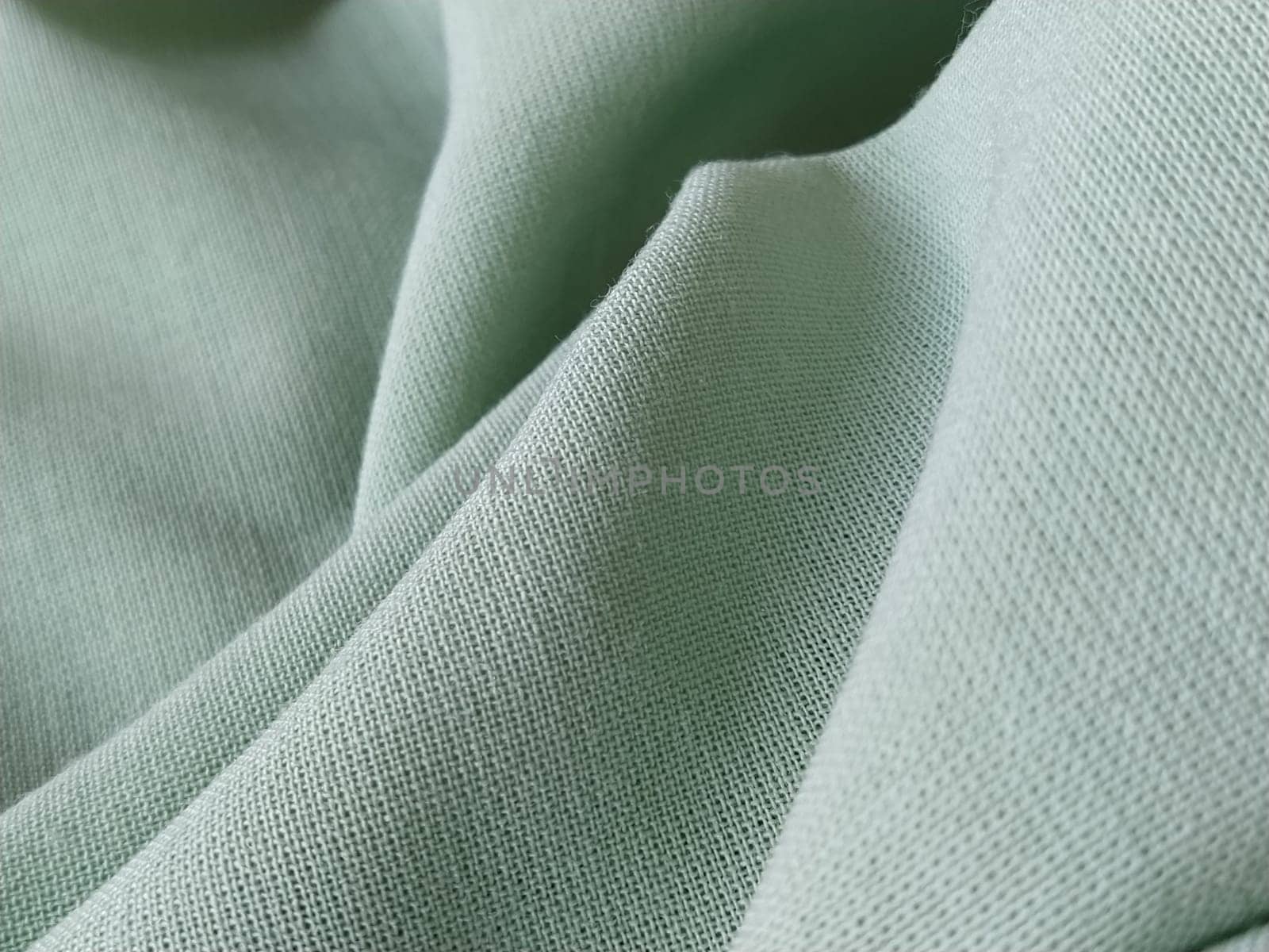 Close up of a woolen fabric of green color. Abstract canvas background, empty template. Thin natural fabric, wool or linen.